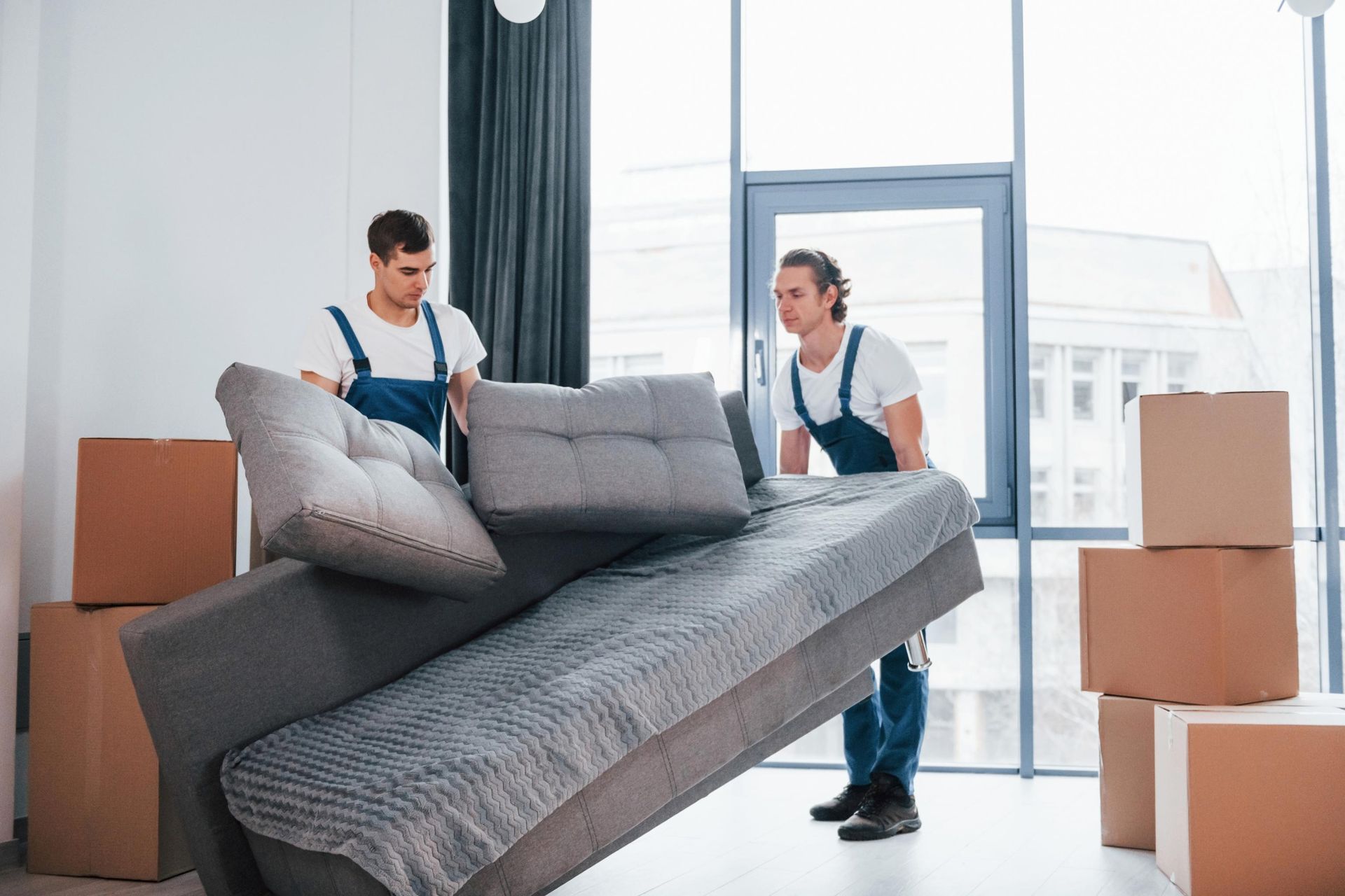Two men are moving a couch in a living room.