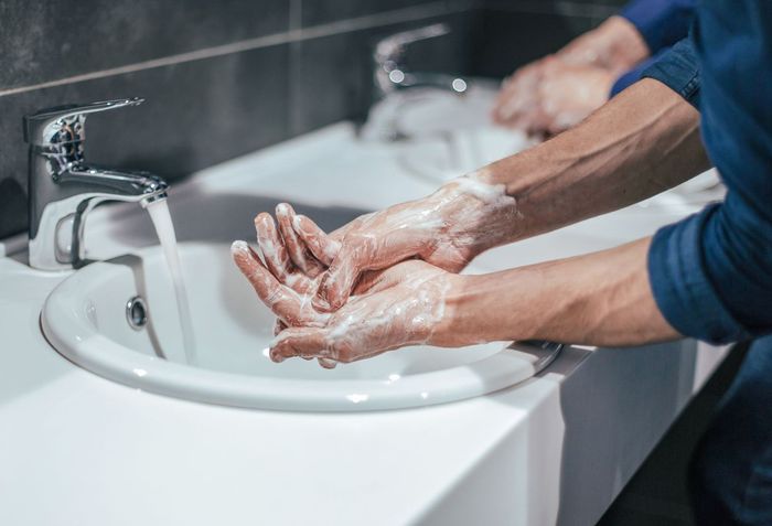 A man is washing his hands in a public restroom sink.