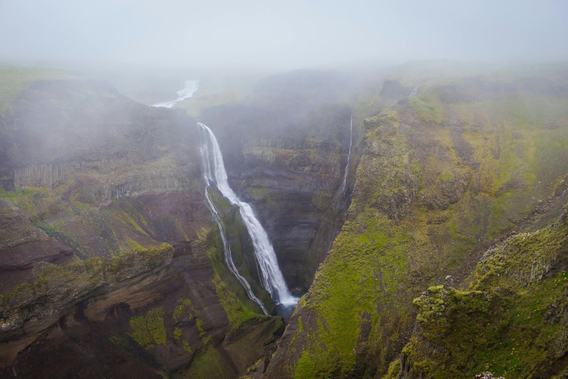 There is a waterfall in the middle of a canyon.