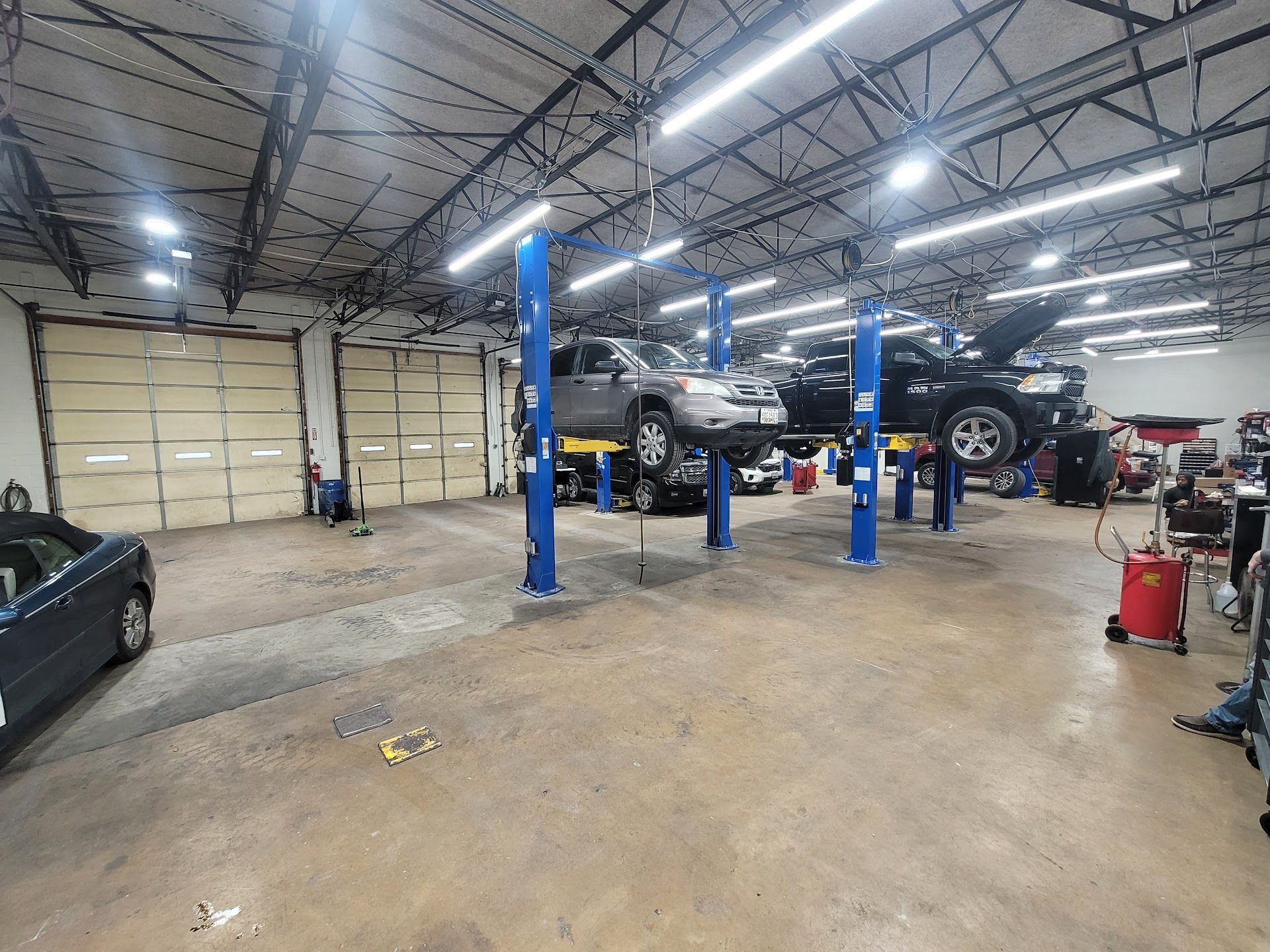 Inside an auto repair shop; several vehicles on lifts, tools and equipment visible. | Zach's Auto Clinic