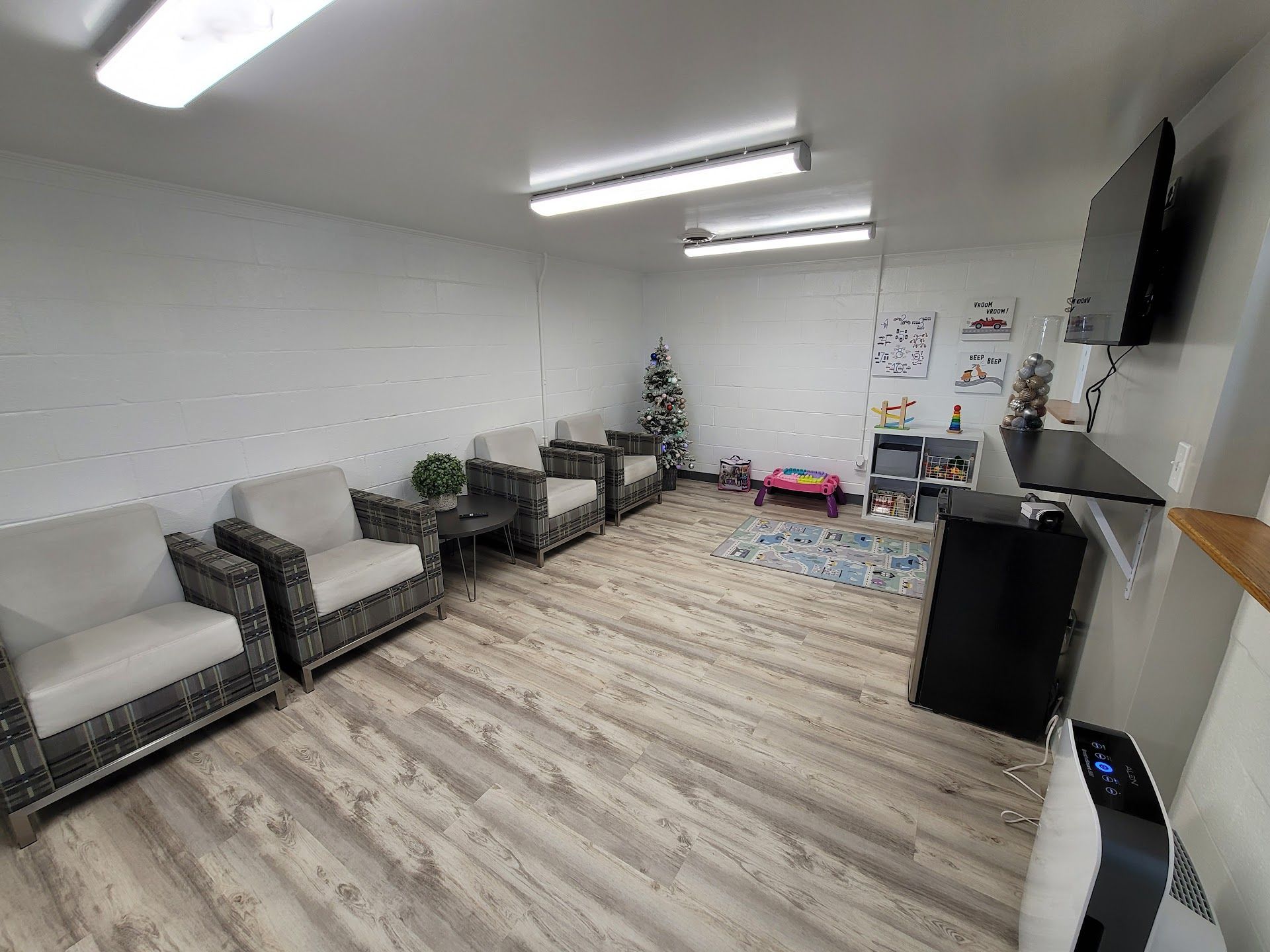 Waiting room with several armchairs, rug, children’s toys, and TV on the wall. | Zach's Auto Clinic