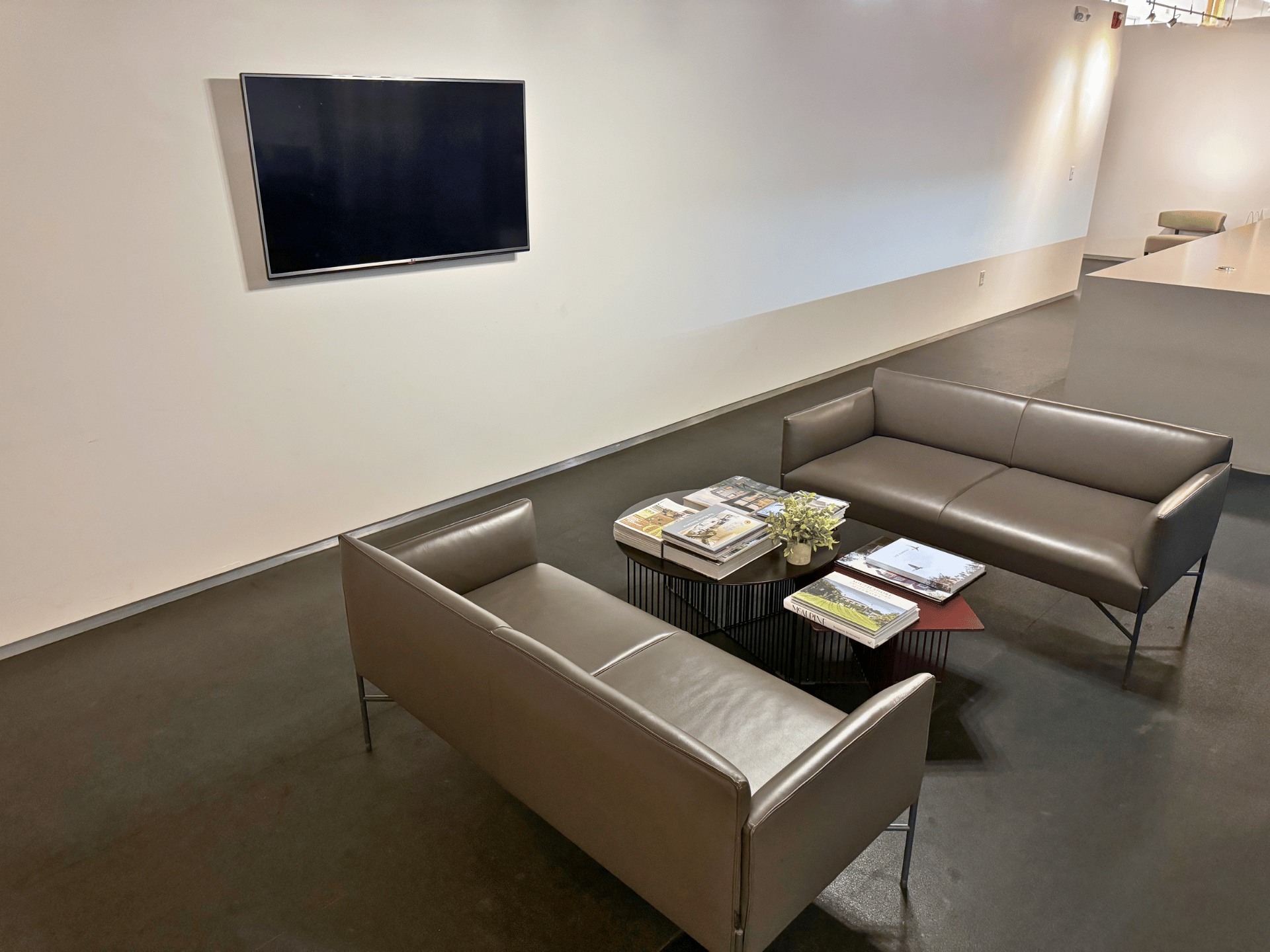 A living room with two couches and a television on the wall in a commercial office in Boston MA. This office reception is cleaned by ThinkFast Cleaning Services.