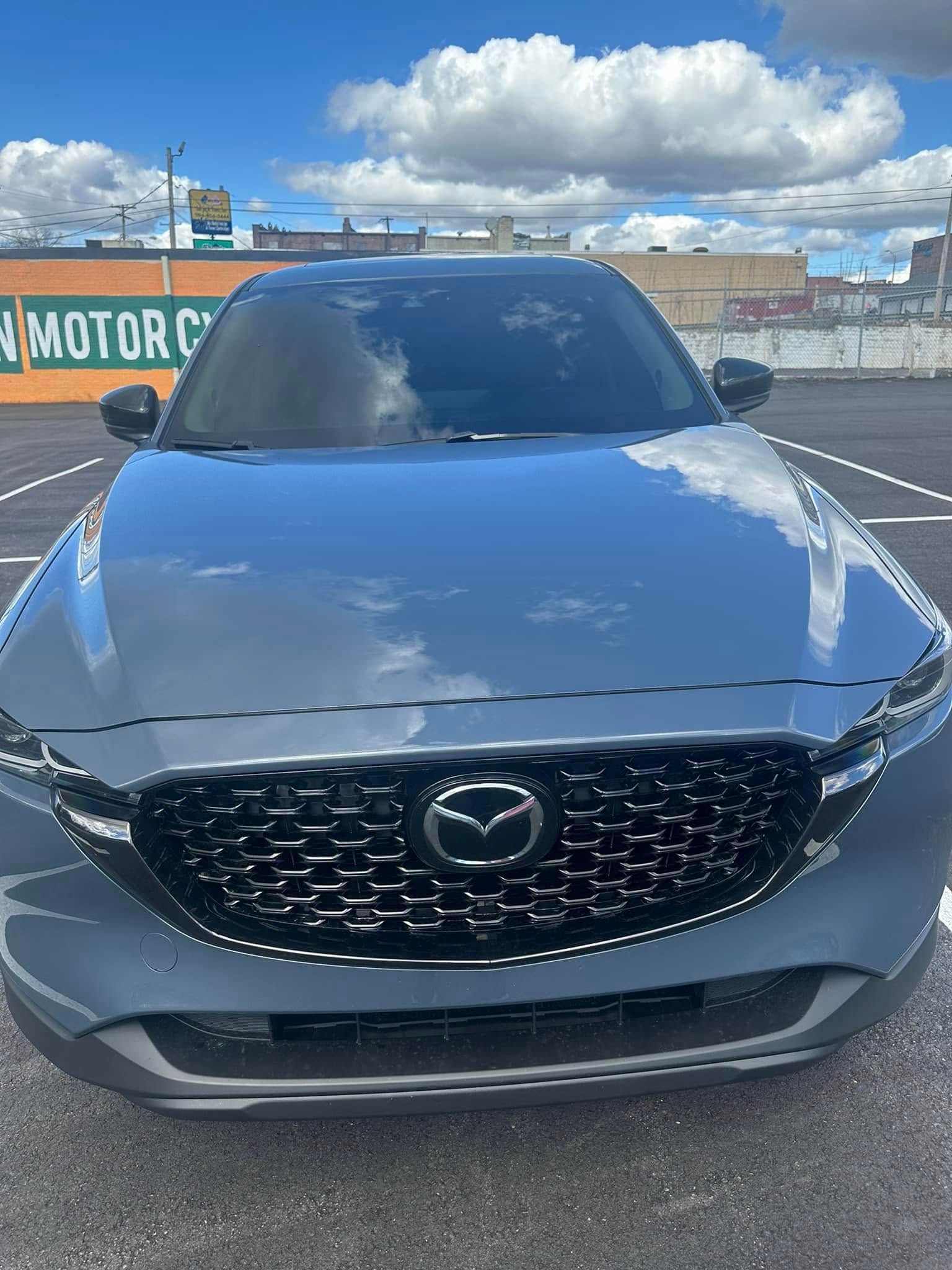Gray Mazda SUV parked in a parking lot on a sunny day.