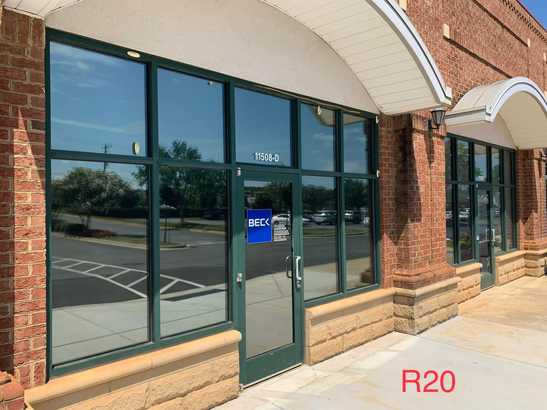 Exterior of a commercial building with large windows and a glass door; brick facade.