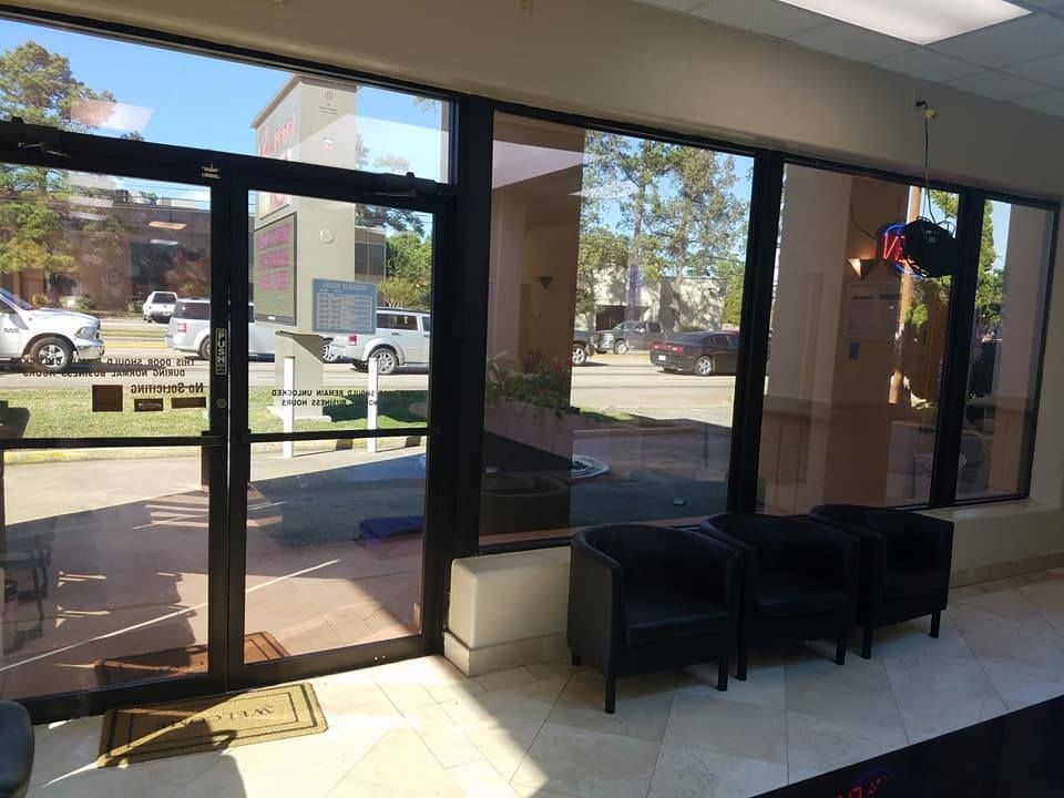 Interior of a business with large tinted windows and black chairs; the outside is visible, street and cars.