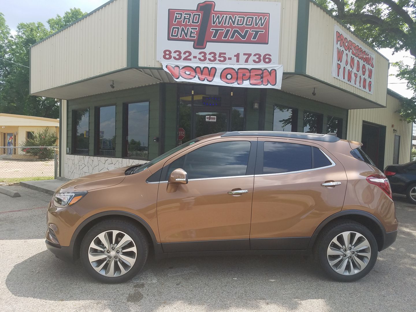 Bronze SUV parked outside a window tinting business with tinted windows. 