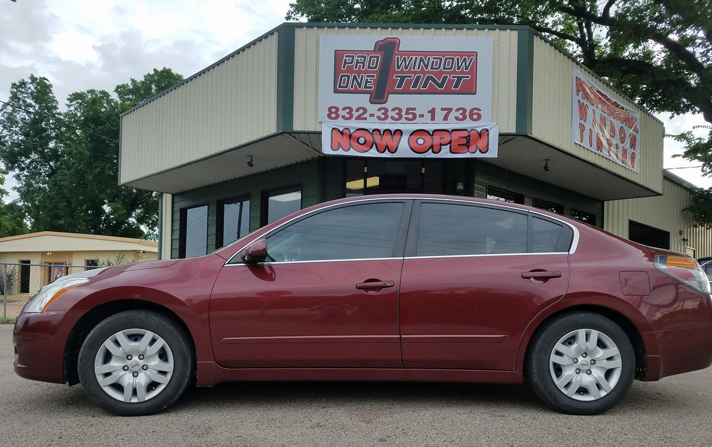 Red sedan parked in front of a car dealership with a 