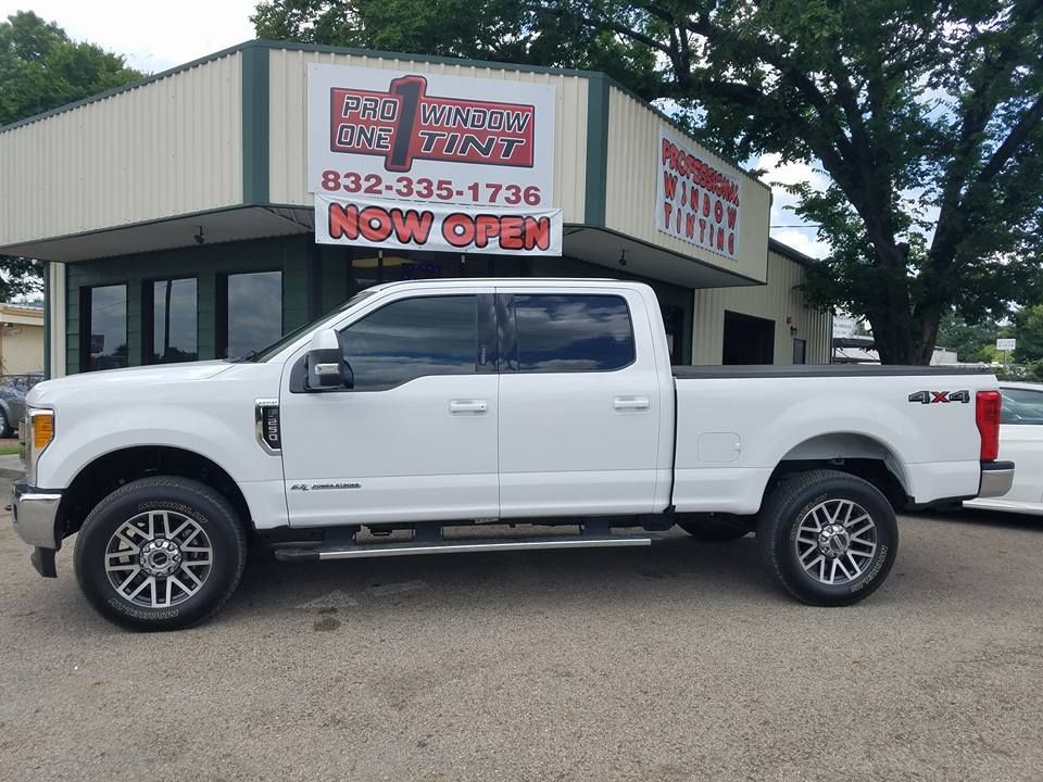White Ford F-250 truck parked in front of a building with a business sign that says 