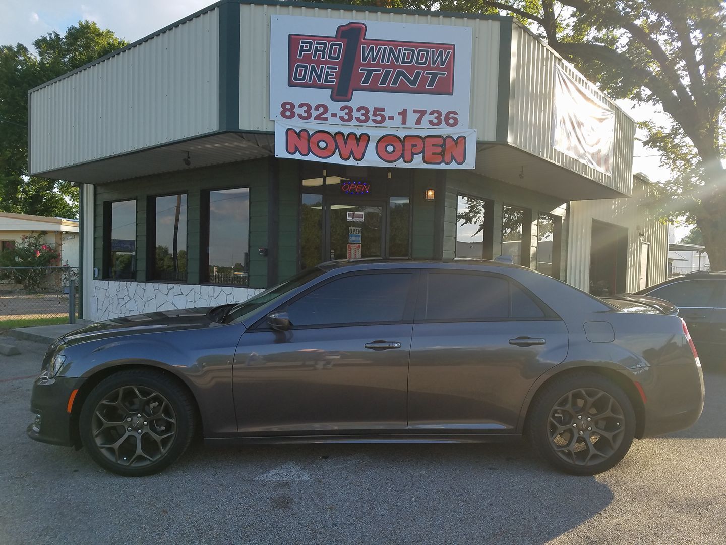 Gray car parked in front of a building with a sign that reads 