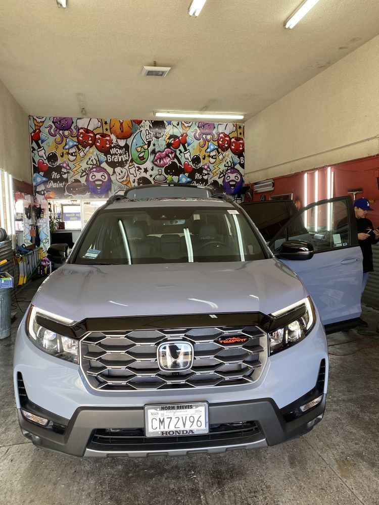 Gray Honda SUV parked in a garage with artwork on the wall and door open.