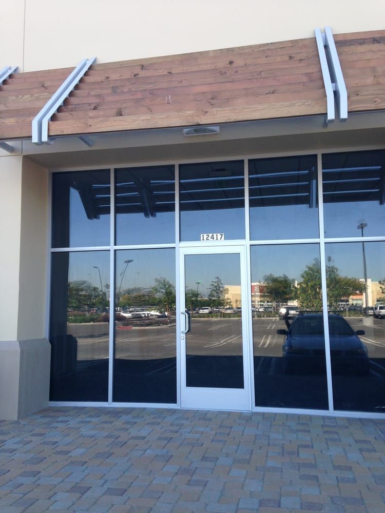 Exterior of a business with glass windows, a door, and a wooden awning. The address 