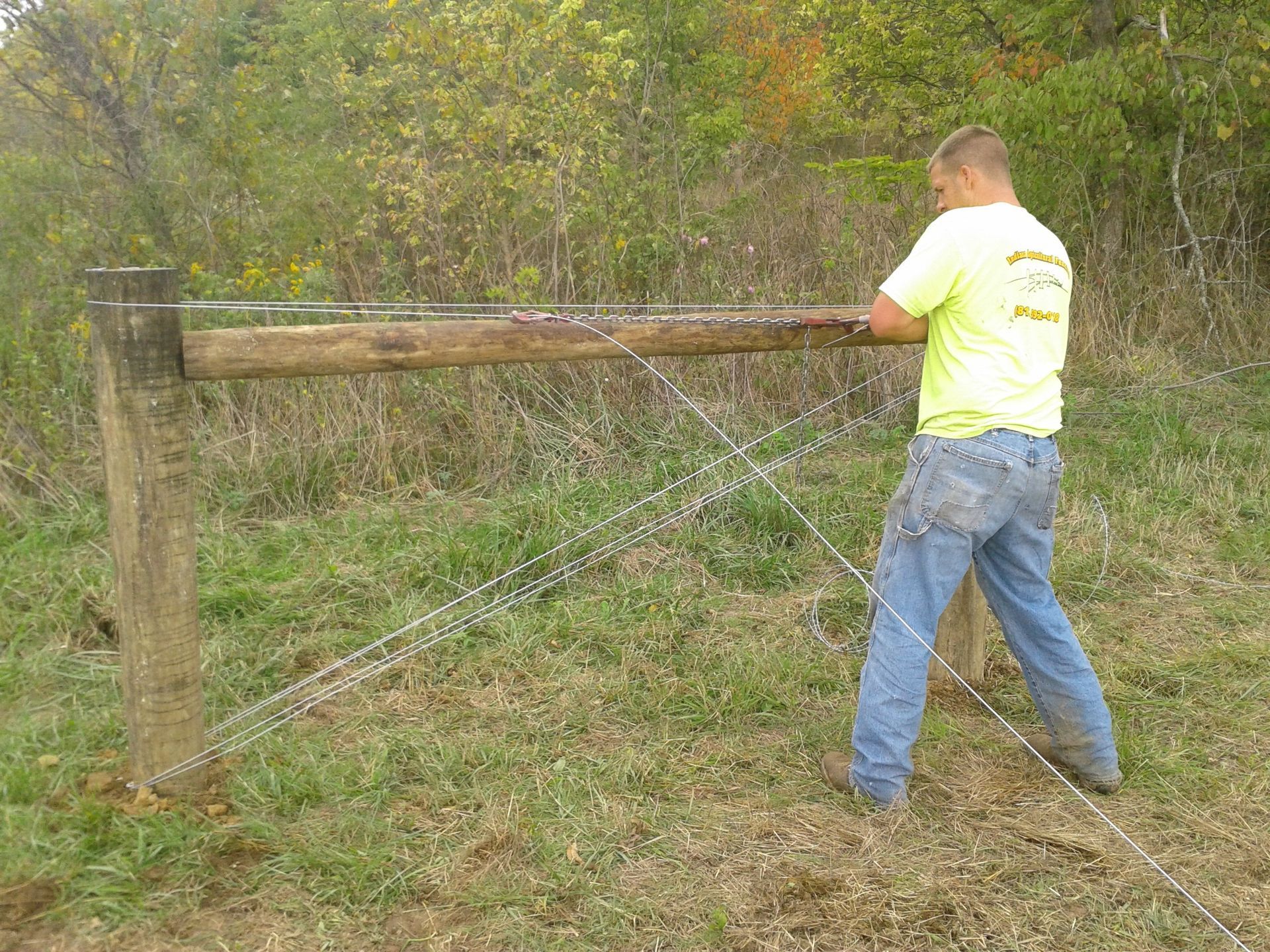 Man Diligently Working On A Fence Using Wire To Secure It - Columbus, IN - Indiana Agricultural Fencing