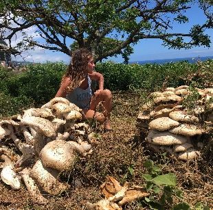 A woman is sitting on top of a pile of mushrooms.