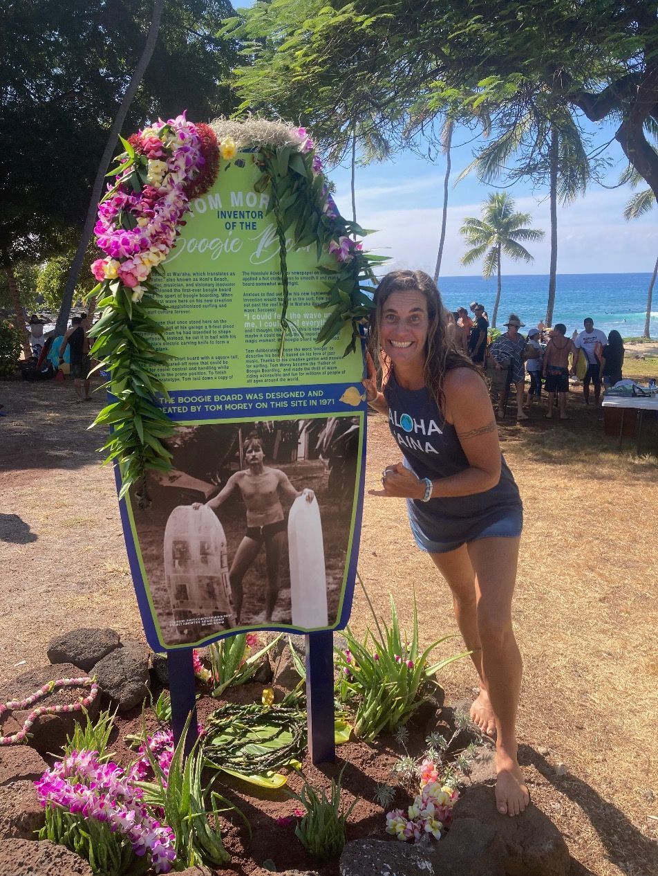 A woman stands in front of a sign that says ' hawaii ' on it
