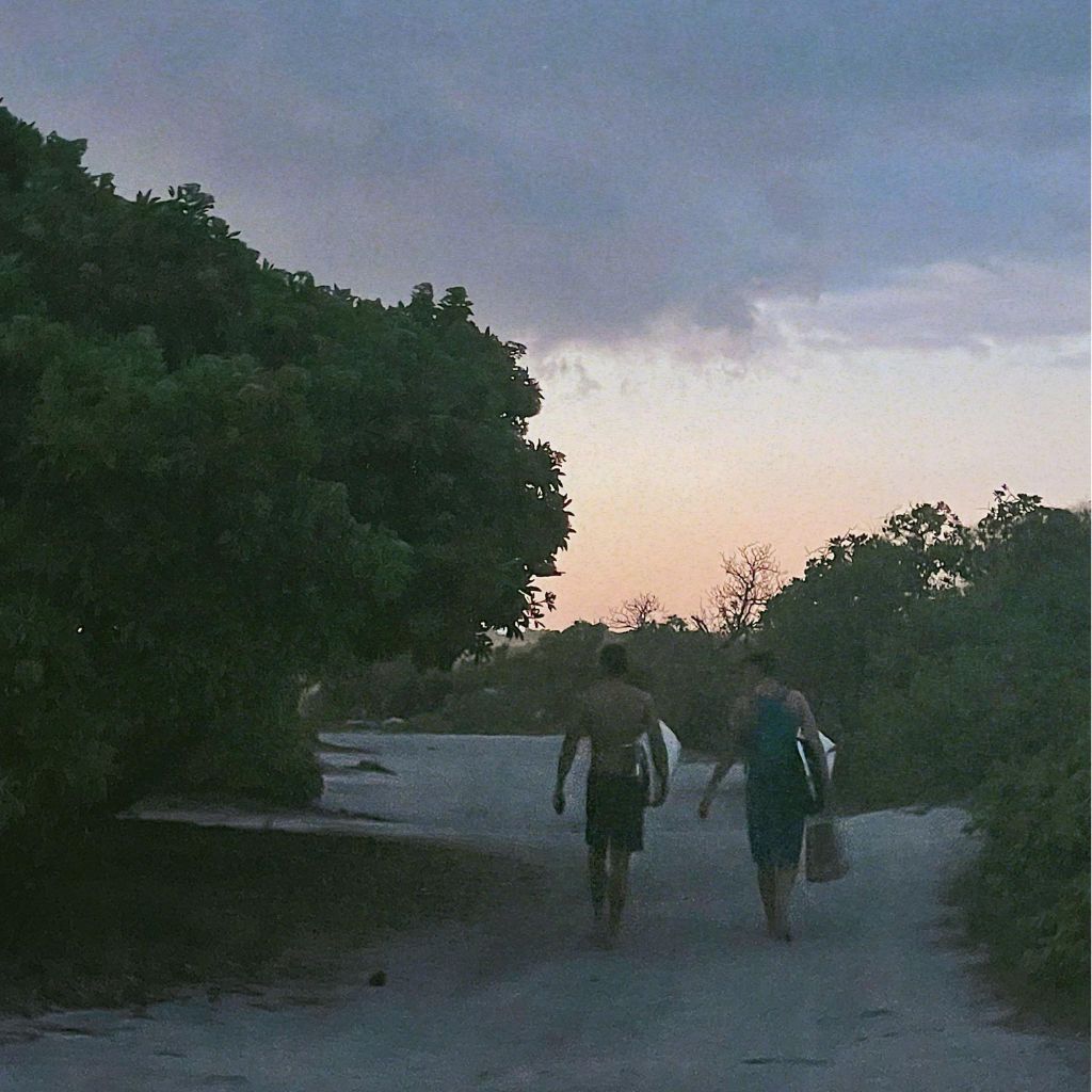 A couple of people walking down a dirt road