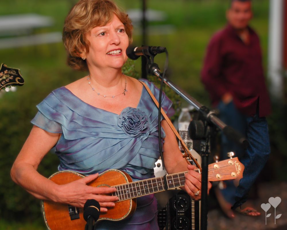 A woman in a blue dress is playing a guitar and singing into a microphone