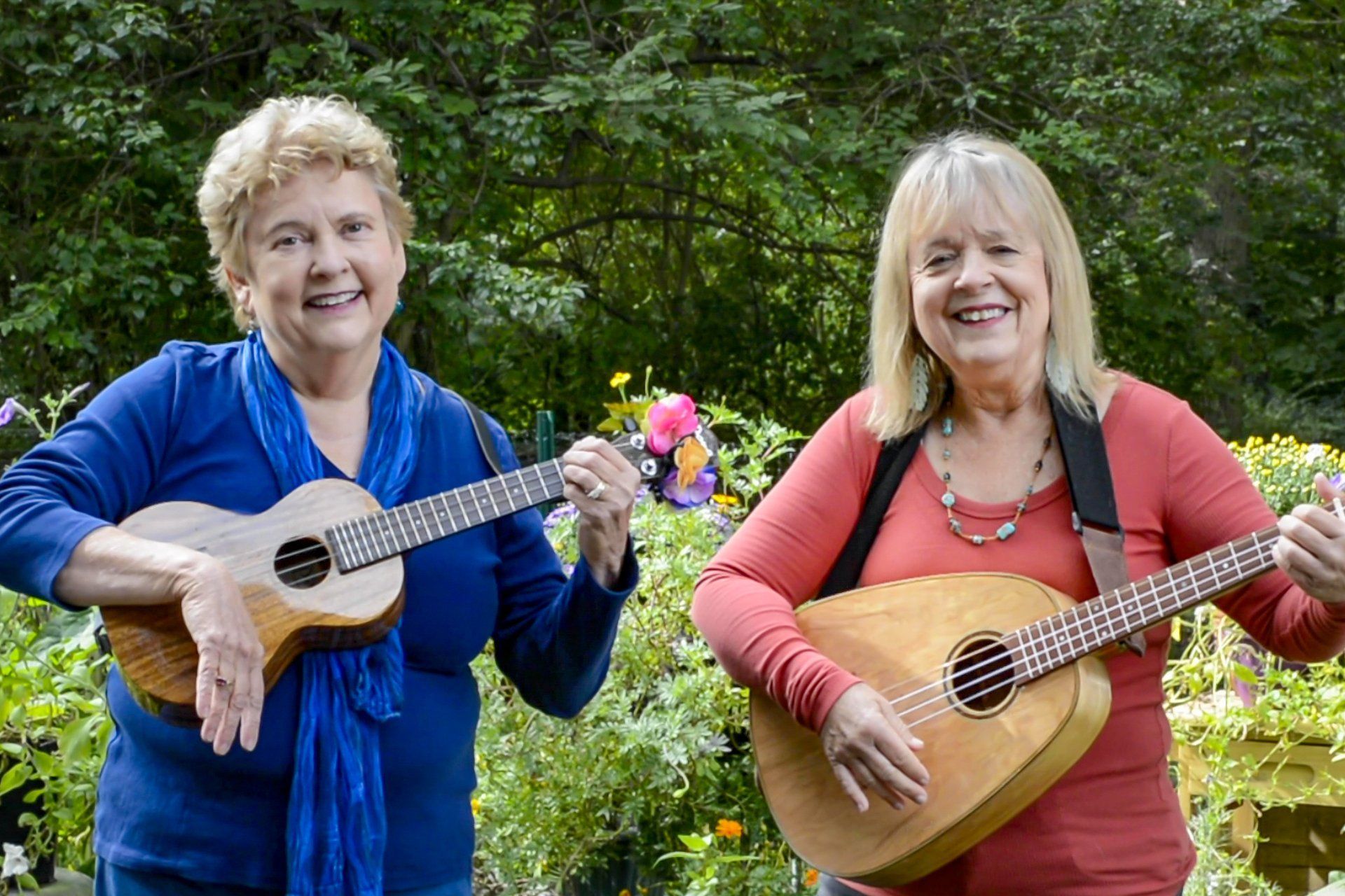 Two women are standing next to each other holding guitars and smiling.