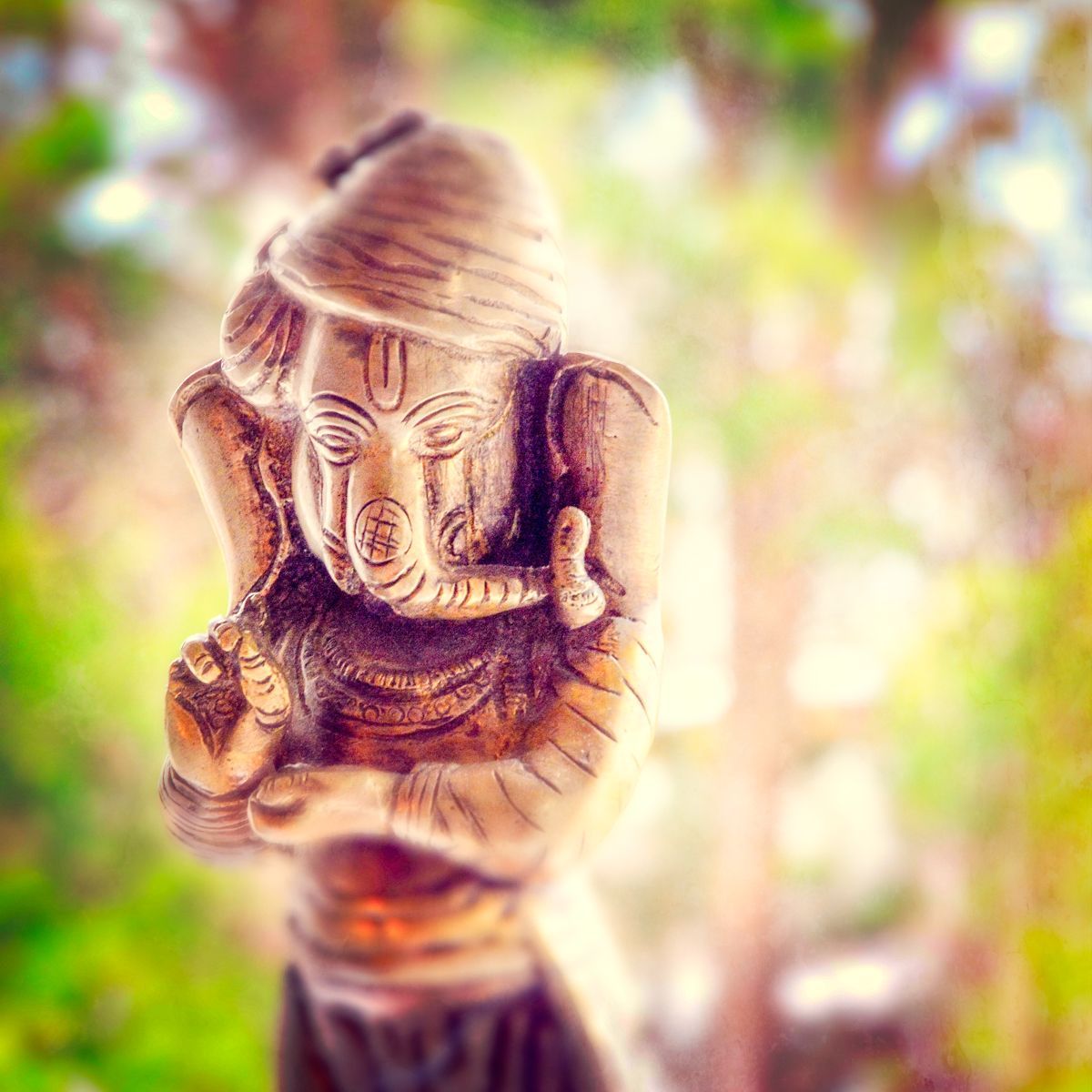 A close up of a statue of a deity with a elephant in his mouth.