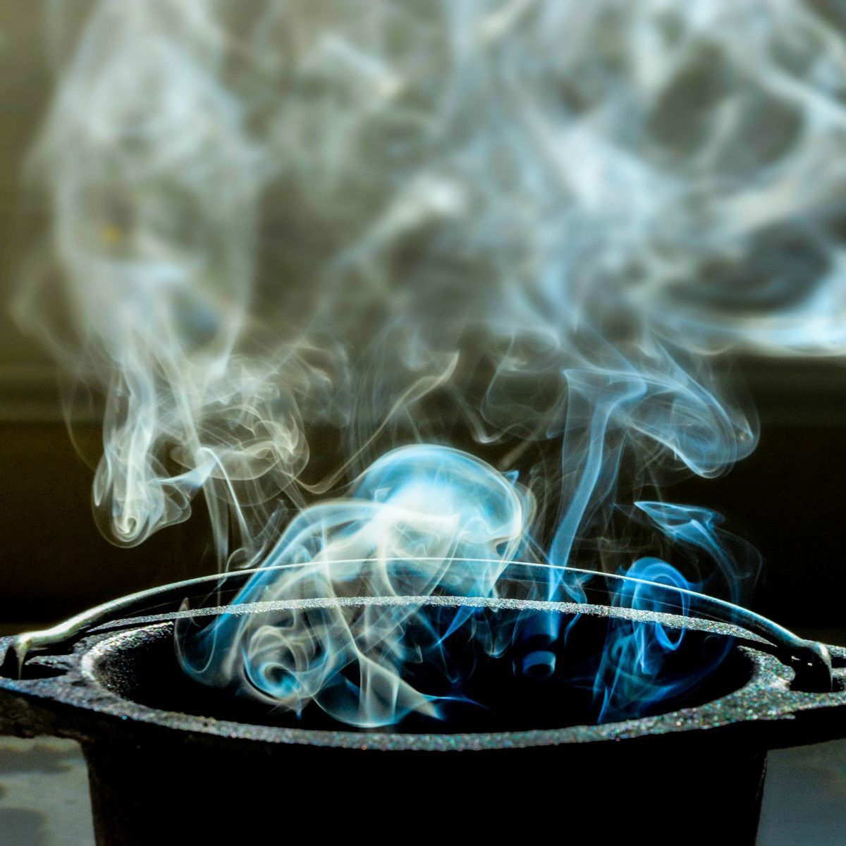Blue smoke is coming out of a black pot