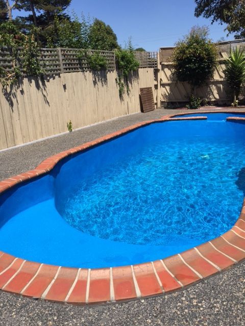 A large blue swimming pool with a brick border