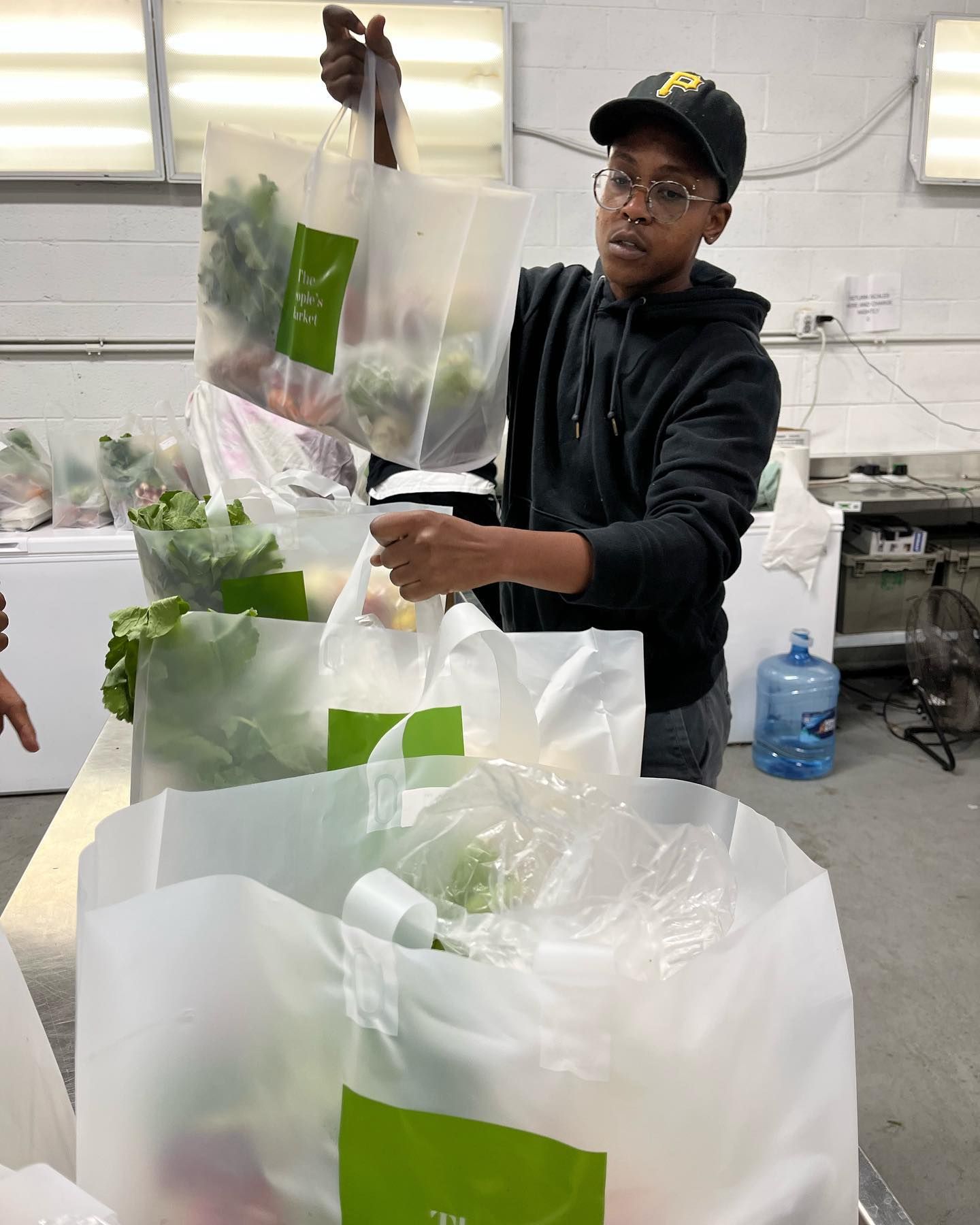 A man is holding a bag of vegetables in a kitchen.