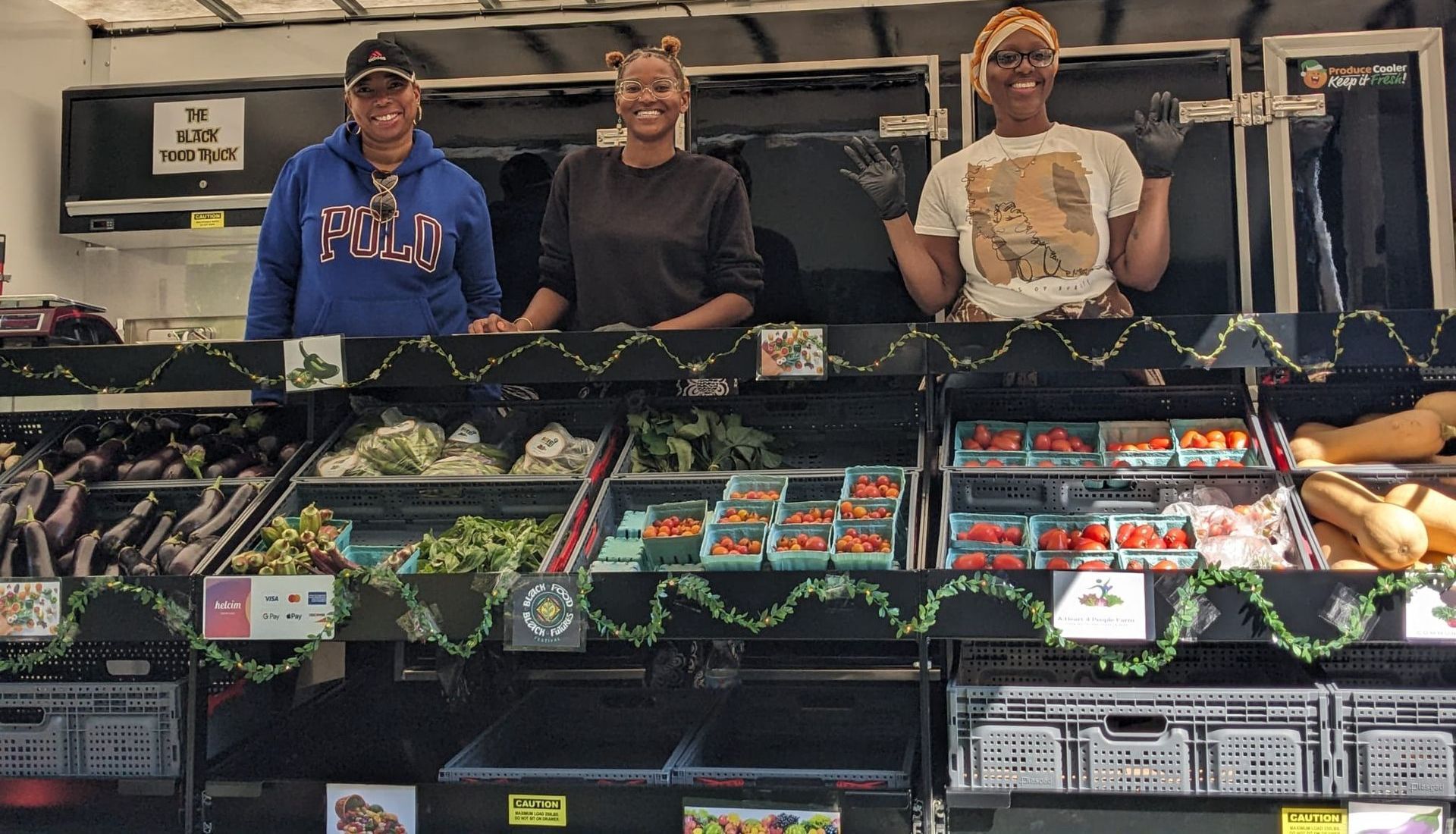Three people are standing in front of a vegetable display in a grocery store.