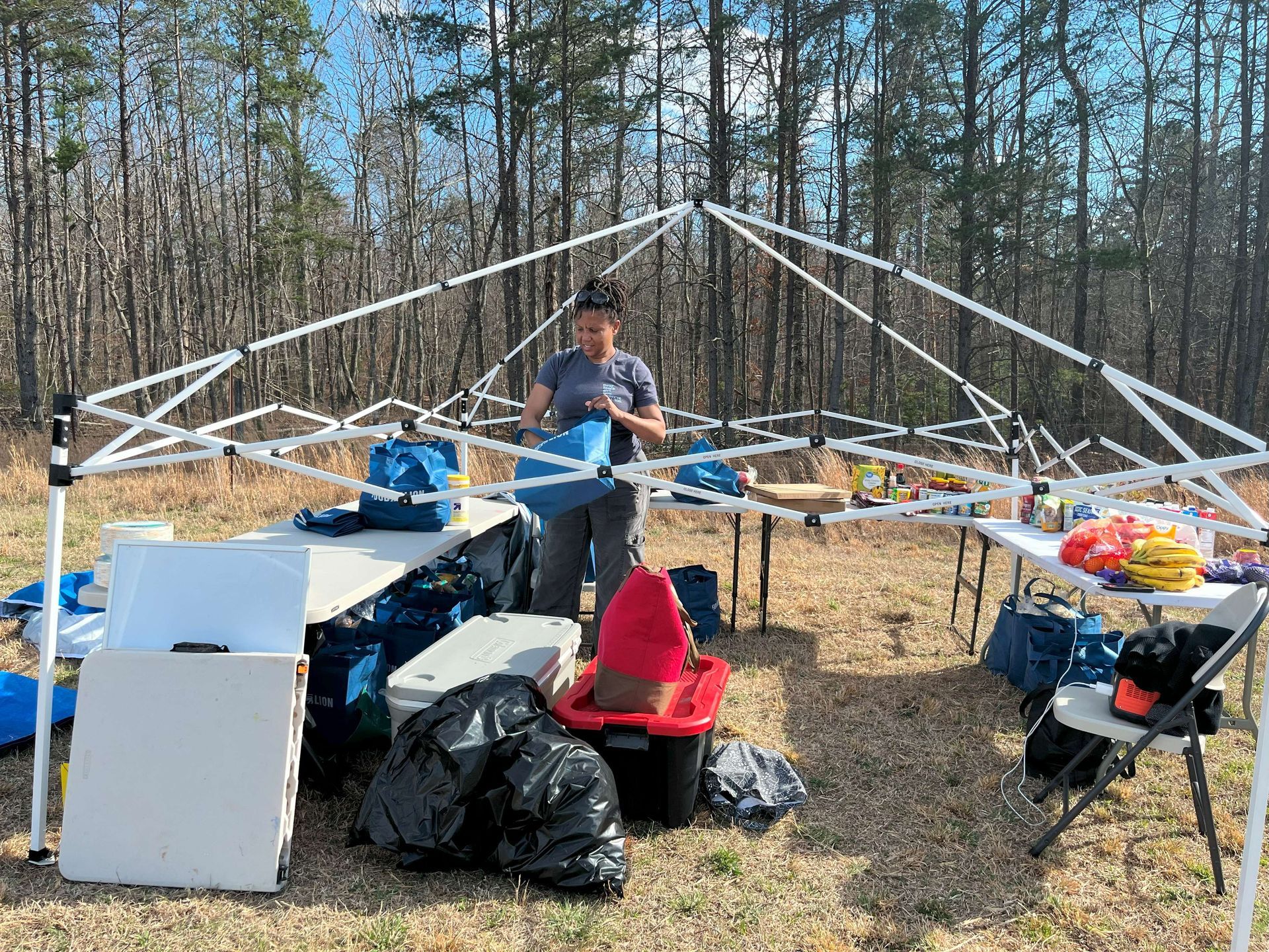 A woman is standing under a tent in a field.