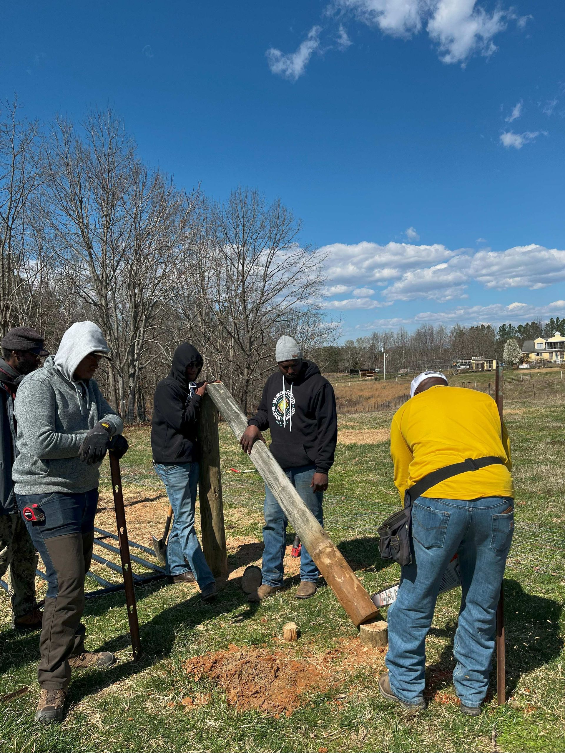 A group of people are working on a fence in a field.