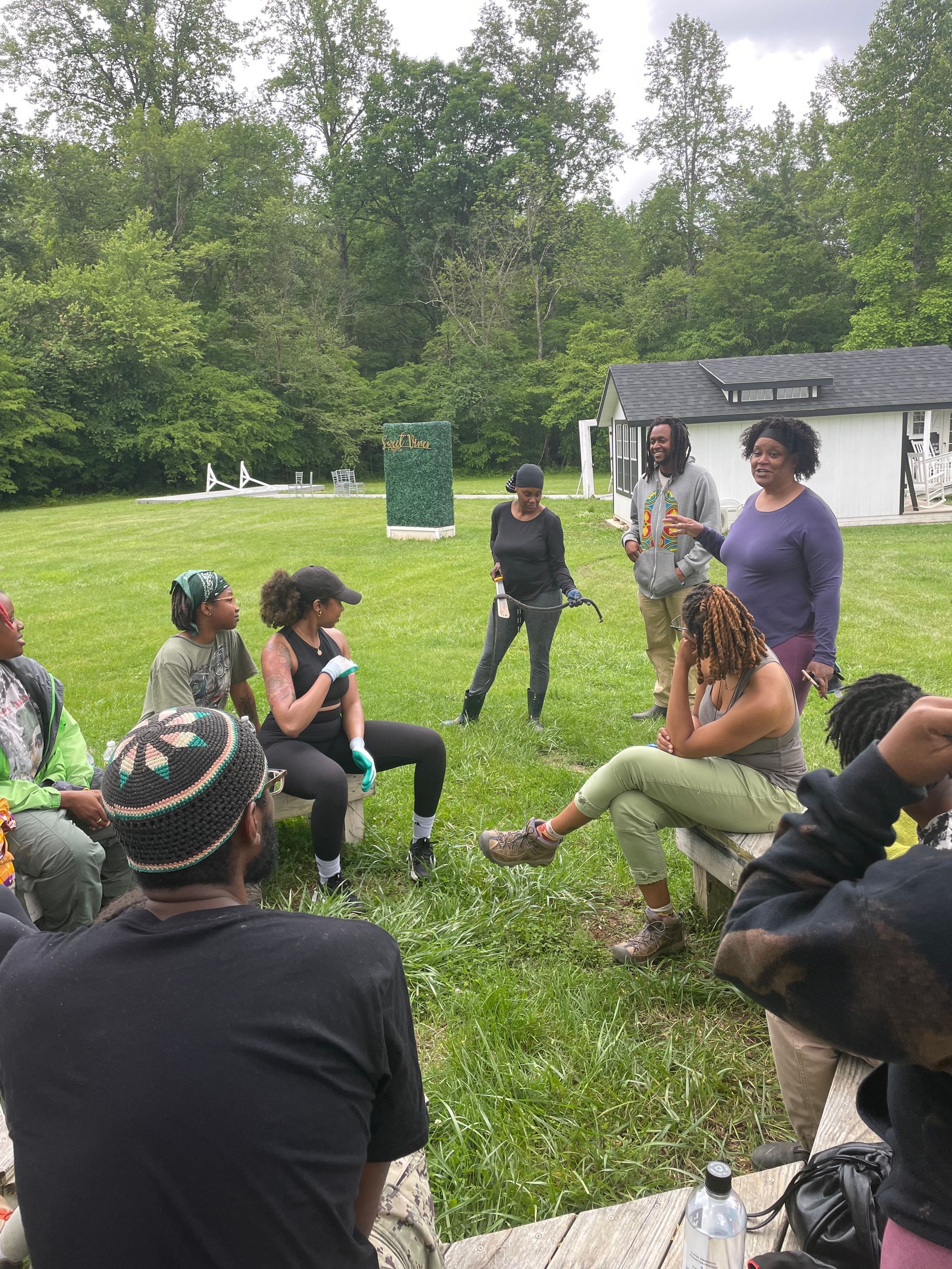 A group of people are sitting in a circle in the grass.