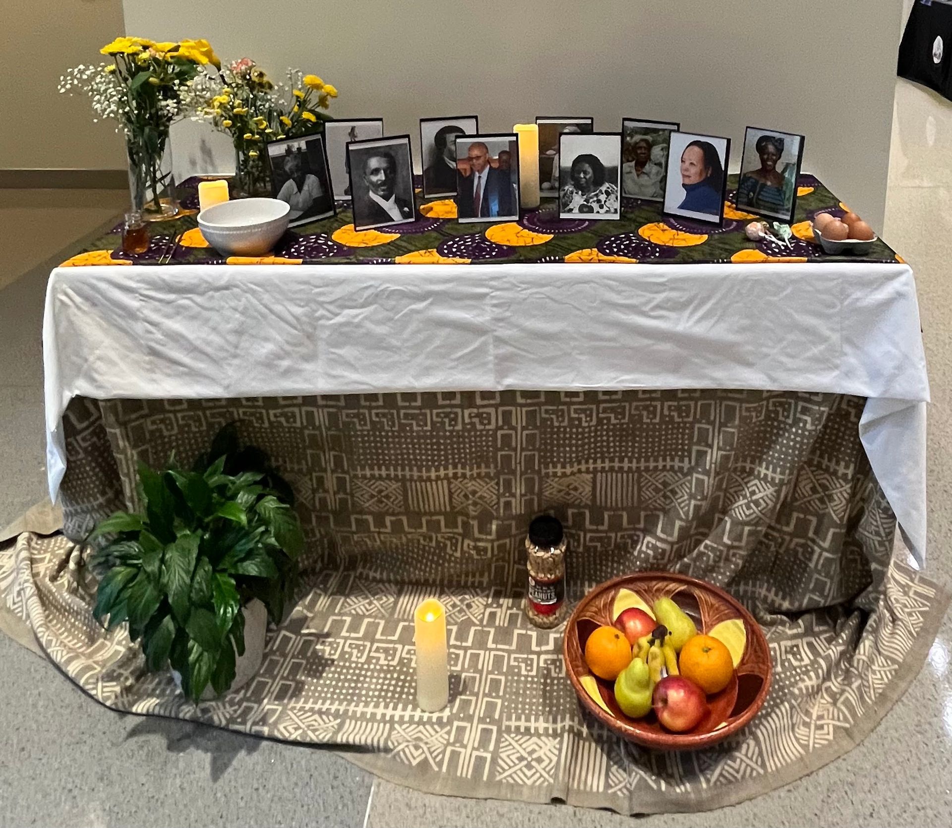 A table with a white table cloth and a bowl of fruit on it.