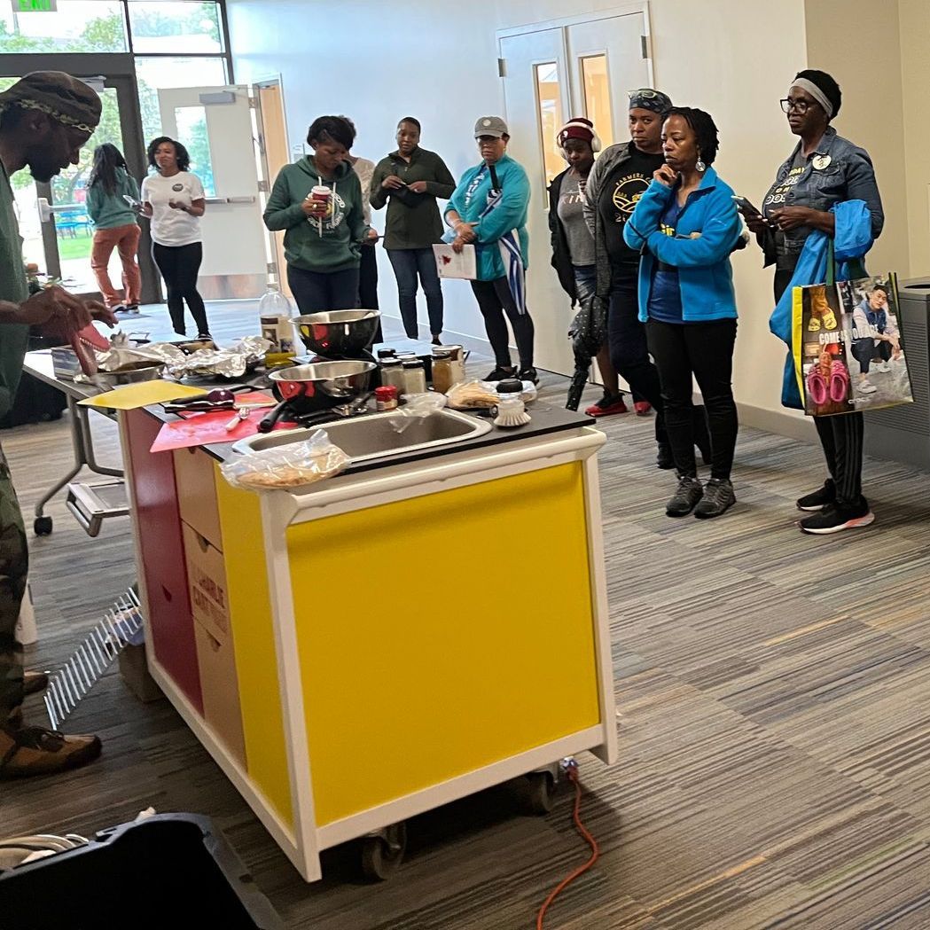 A group of people are standing around a table with food on it