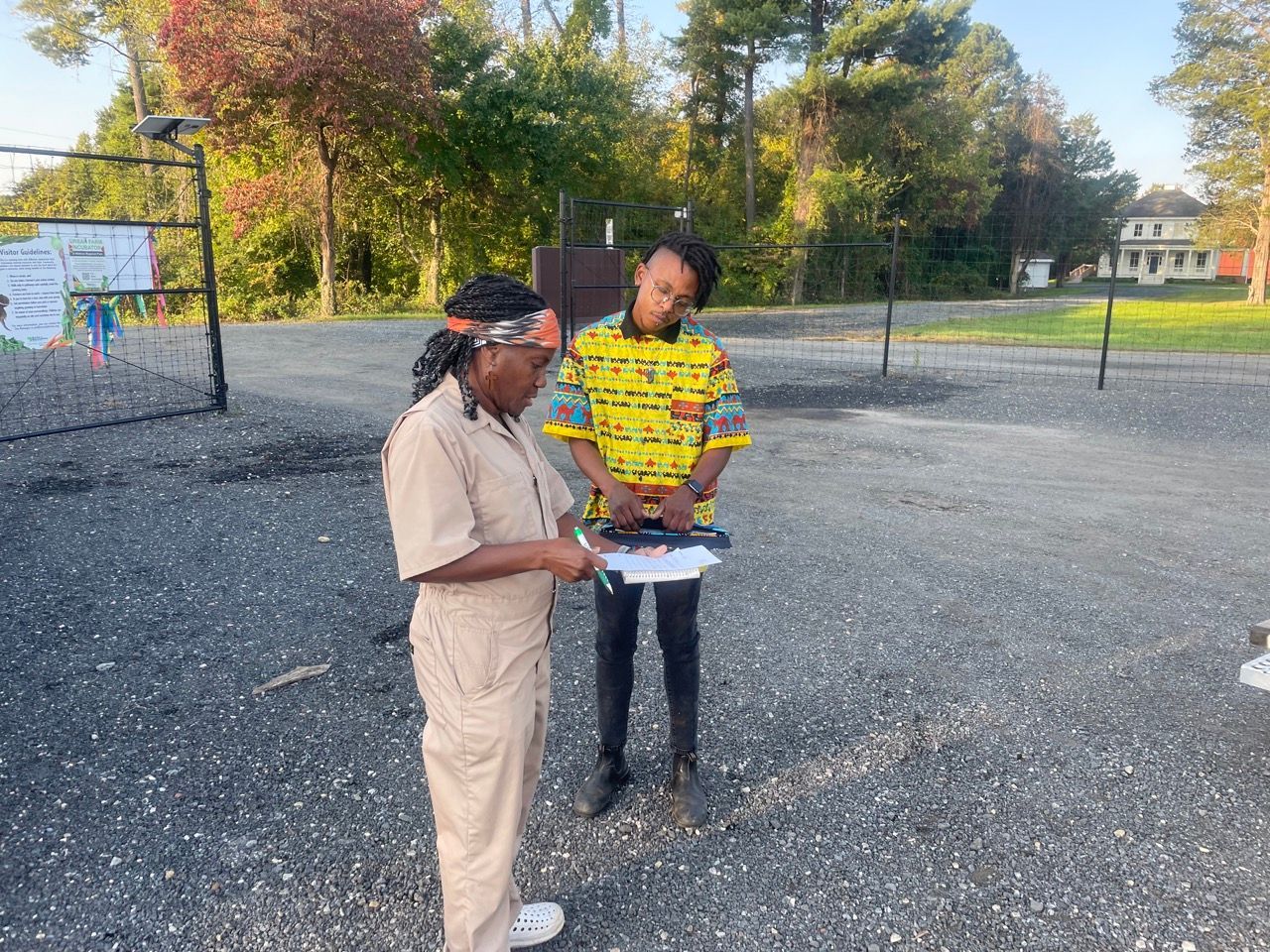 A man and a woman are standing in a parking lot looking at a clipboard.