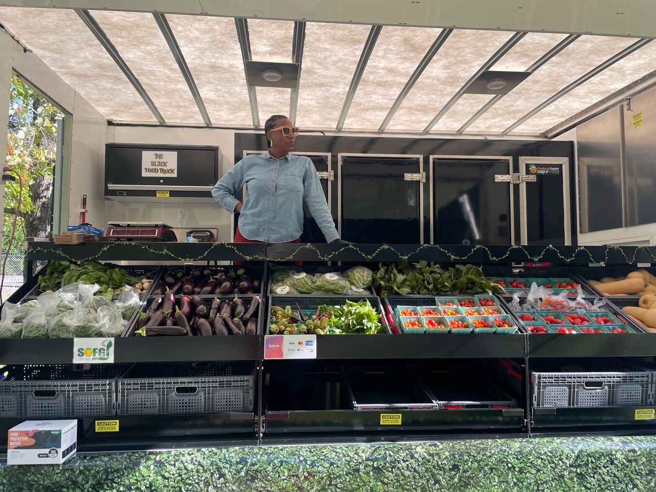 A man is standing in front of a display of fruits and vegetables.