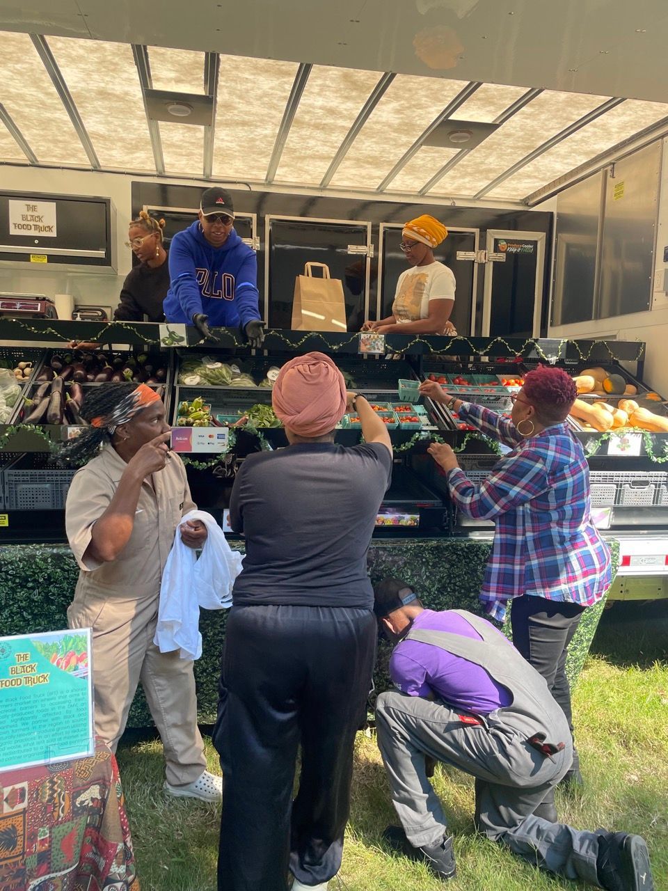 A group of people are standing in front of a fruit stand.