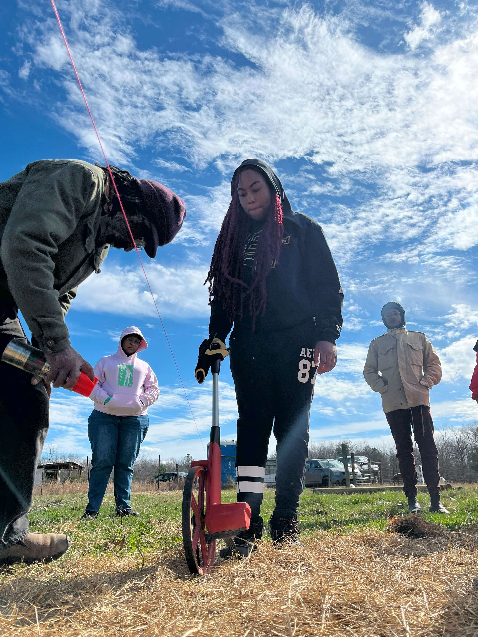 A group of people are standing in a field using a measuring device.