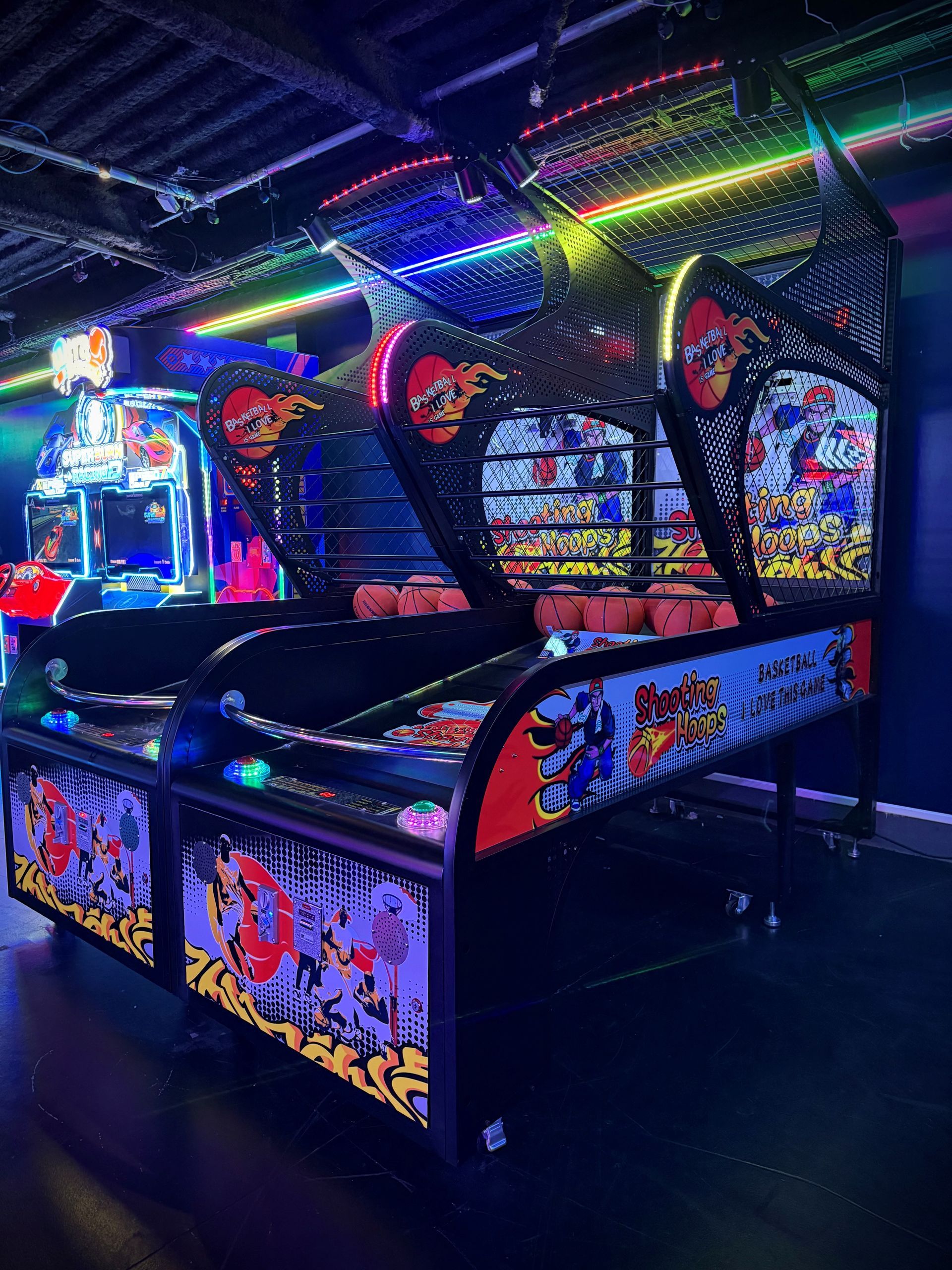 Basketball arcade game in a dimly lit arcade, lit by colorful neon lights.