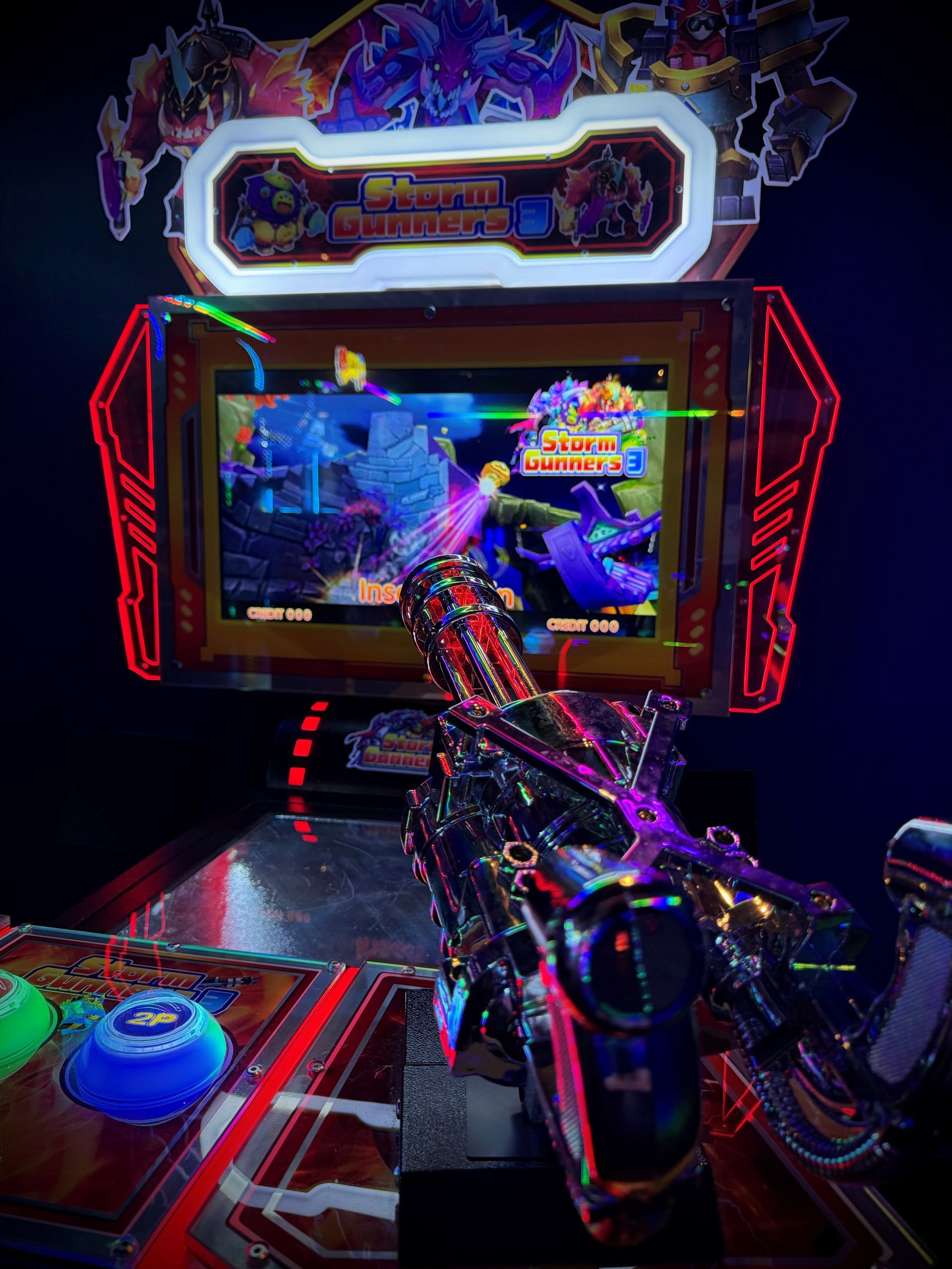 Arcade game, colorful with a large screen, gun-shaped controller, dark setting.