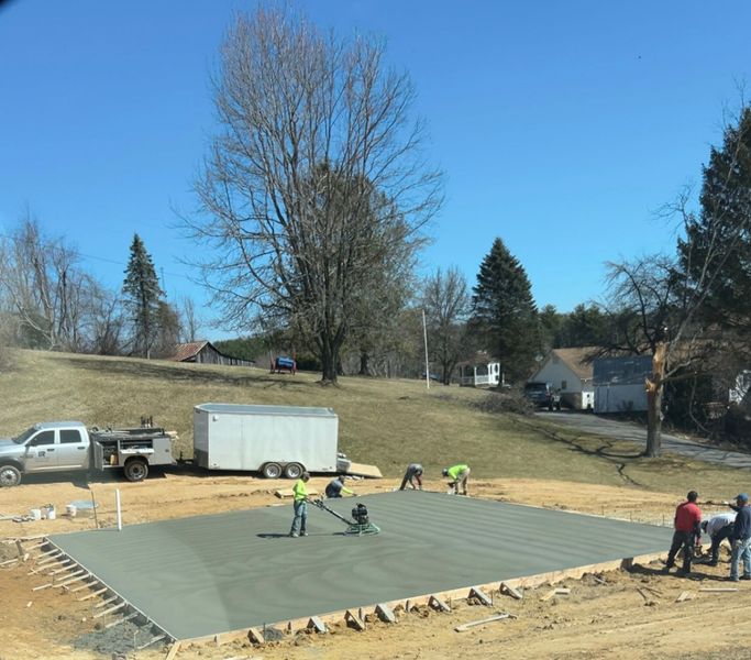 Workers smoothing concrete on a foundation slab at a construction site on a sunny day