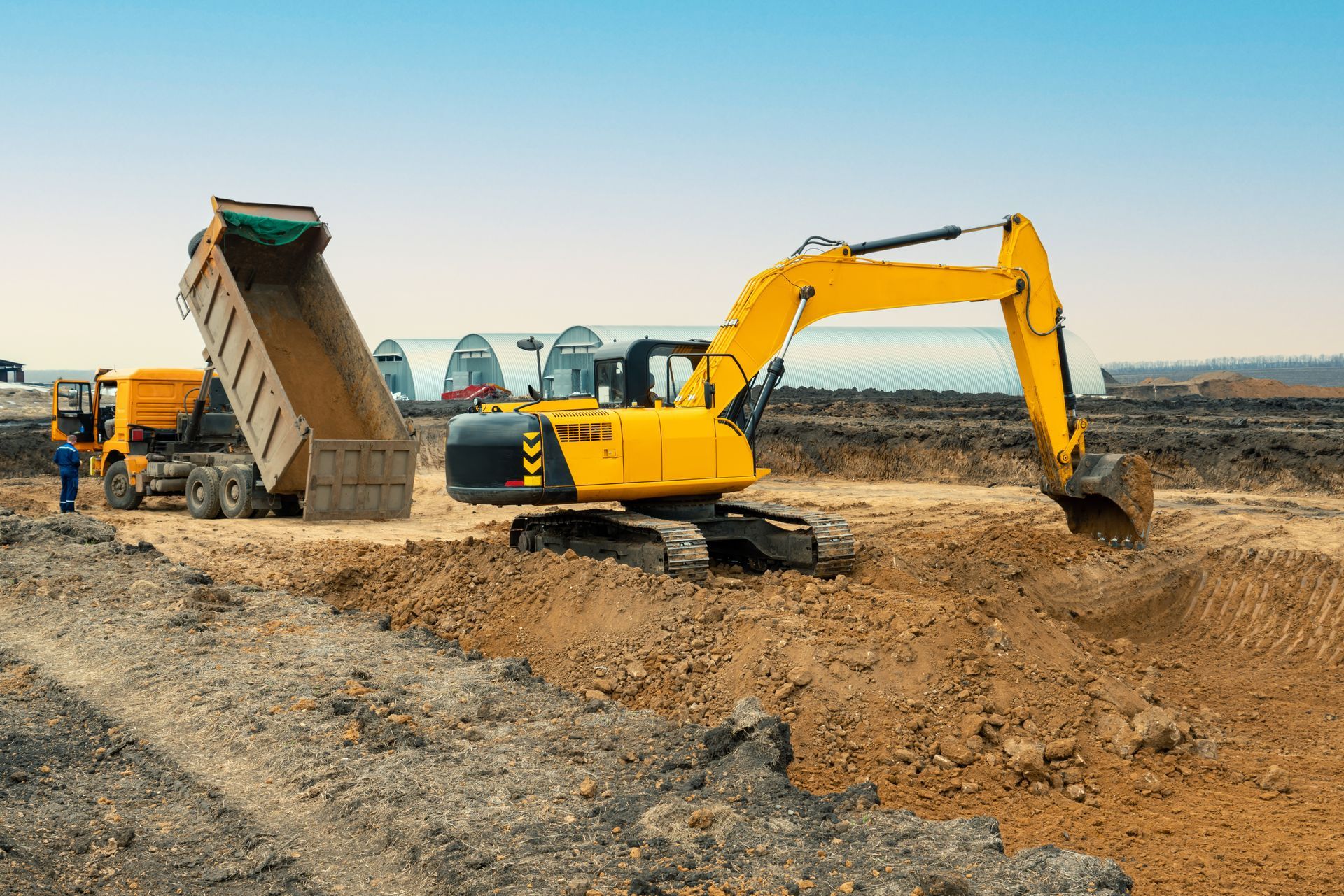 Yellow excavator loading dirt into a dump truck on a construction site
