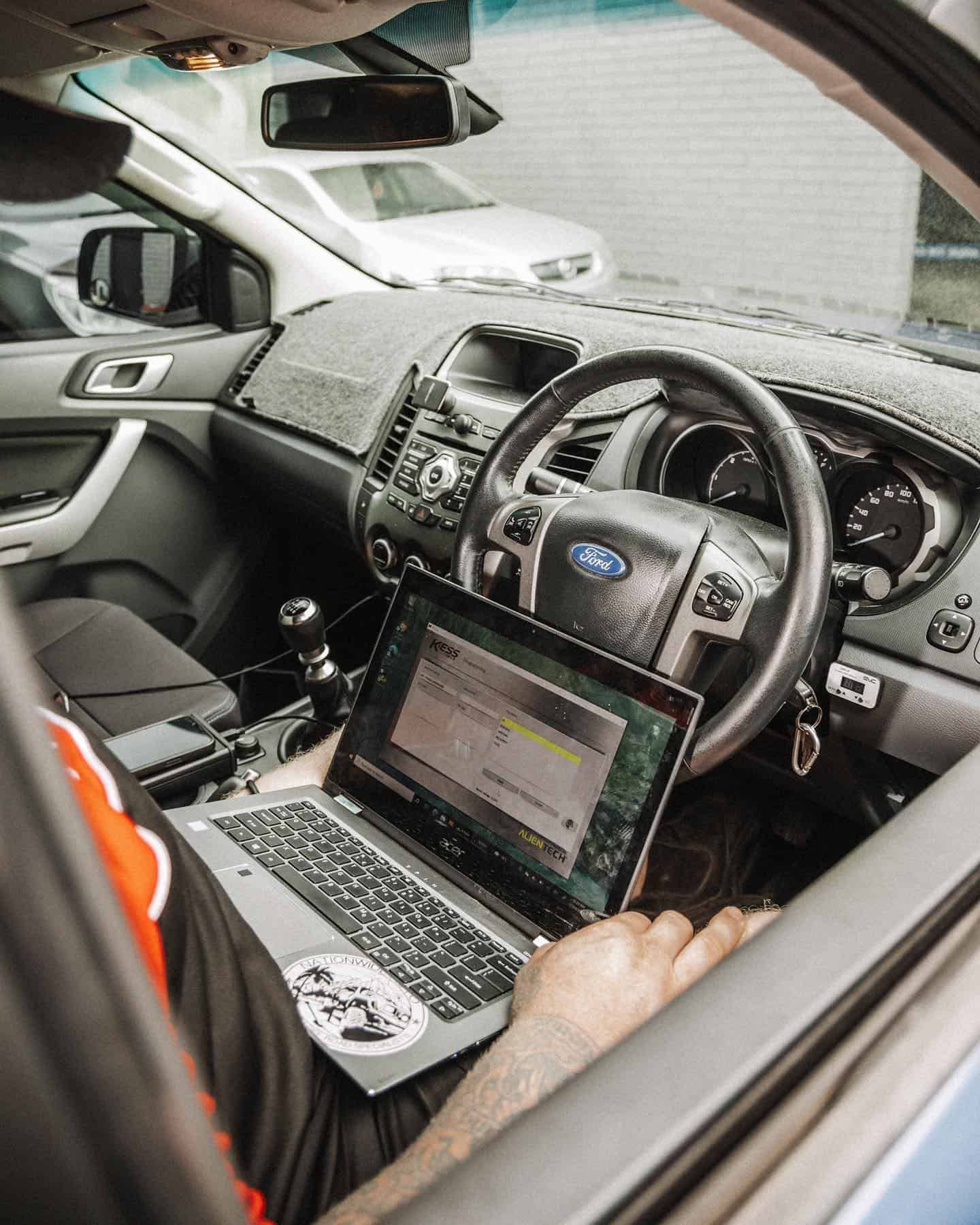 Person in Ford Ranger cabin uses laptop. Interior shot, hands visible, car parked. — Nationwide Auto Service Centre in West Gosford, NSW