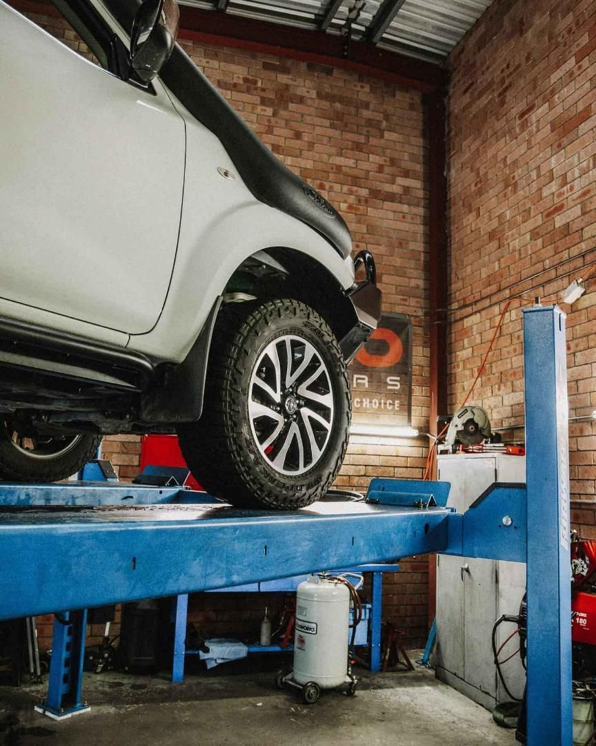 A White Truck is Sitting on Top of a Blue Lift in a Garage — Nationwide Auto Service Centre in West Gosford, NSW