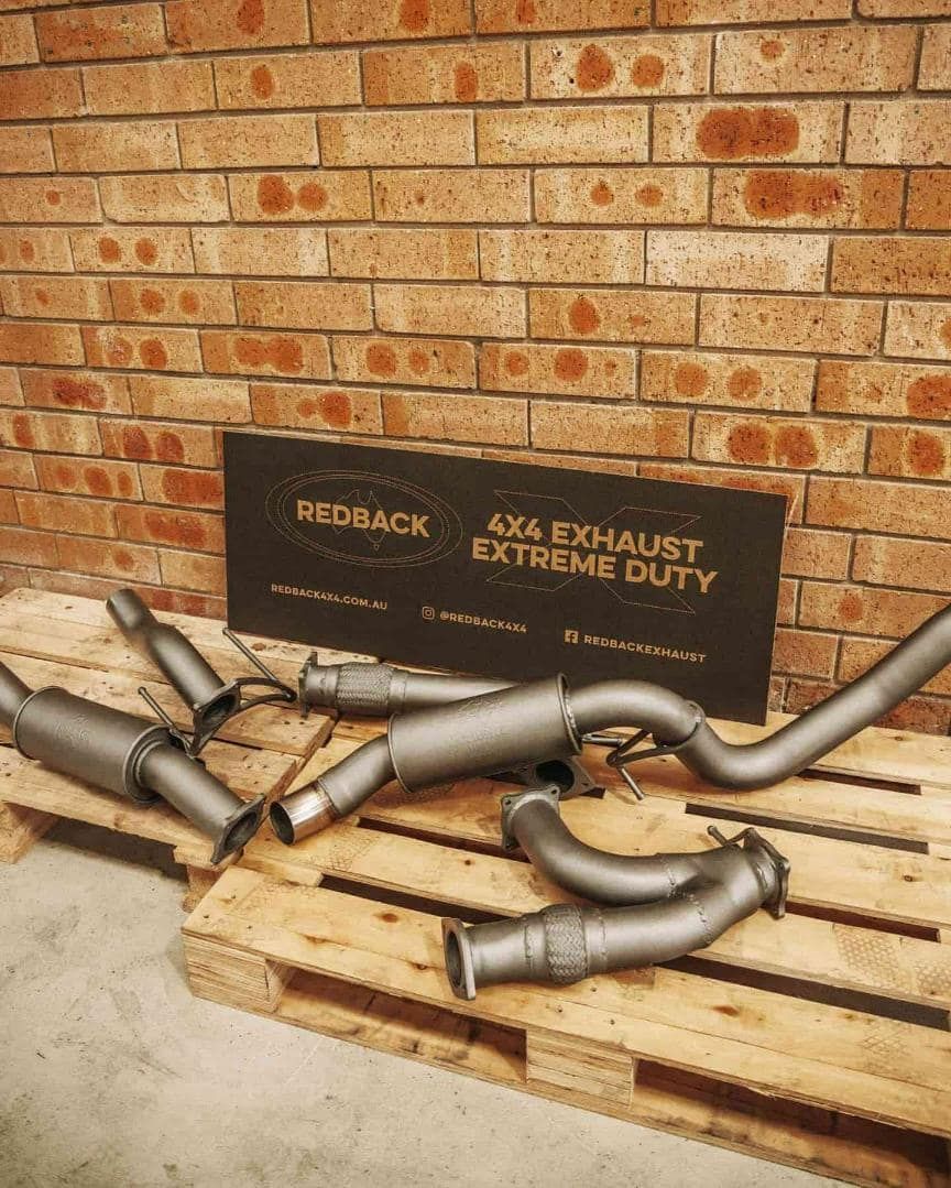 Exhaust Pipes Are Sitting on a Wooden Pallet in Front of a Brick Wall — Nationwide Auto Service Centre in West Gosford, NSW