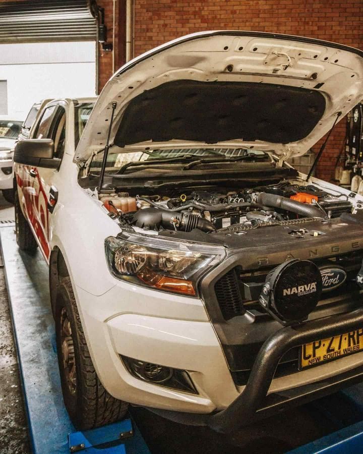 A White Truck With the Hood Up is Sitting on a Lift in a Garage
— Nationwide Auto Service Centre in West Gosford, NSW