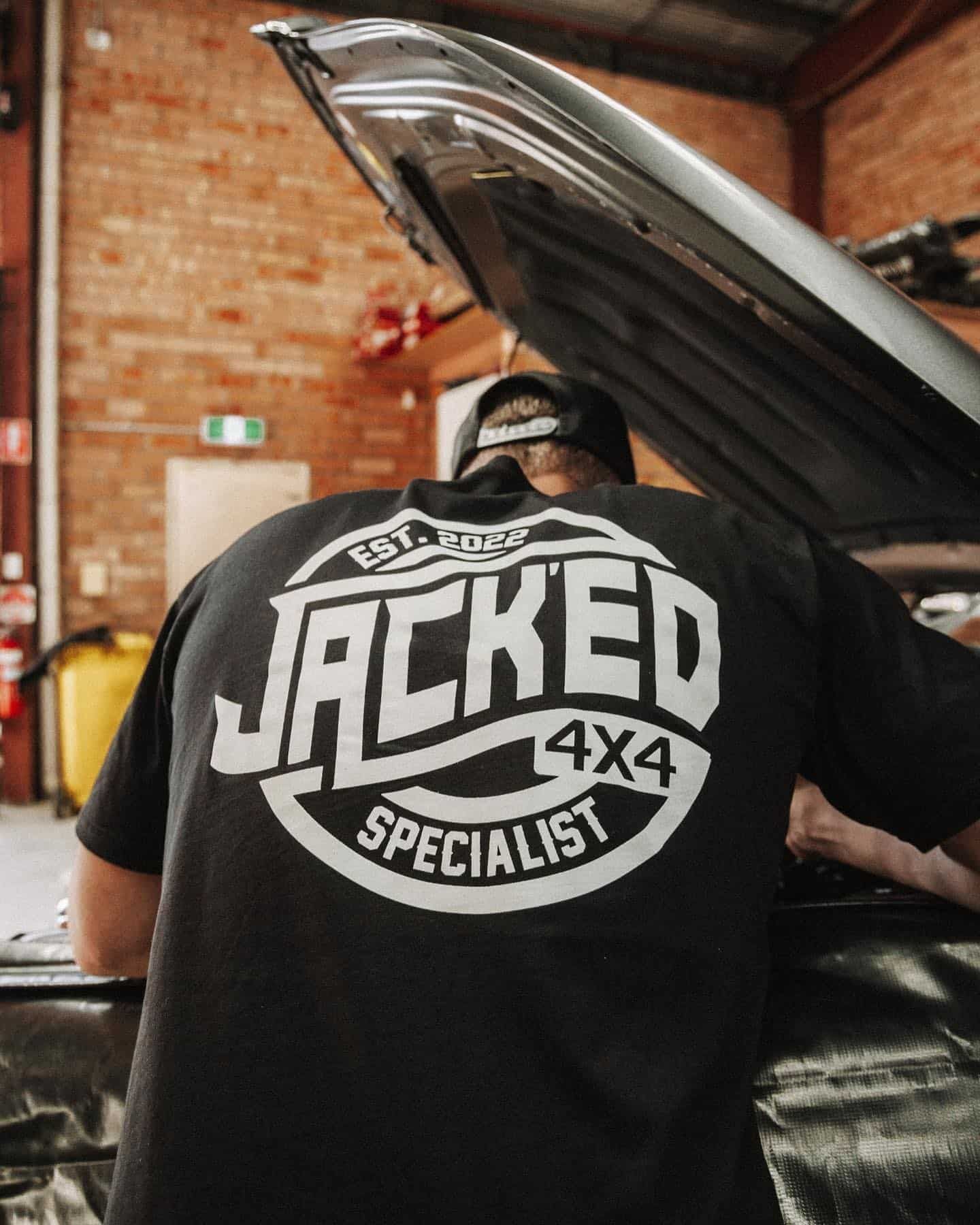 A Man Wearing a Black Shirt That Says Jacked 4x4 Specialist — Nationwide Auto Service Centre in West Gosford, NSW