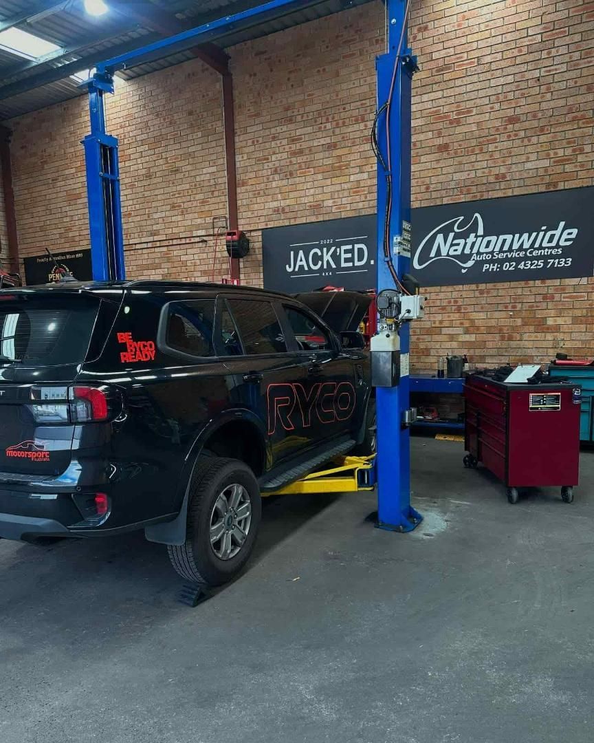 A Black Suv is Sitting on a Lift in a Garage — Nationwide Auto Service Centre in West Gosford, NSW