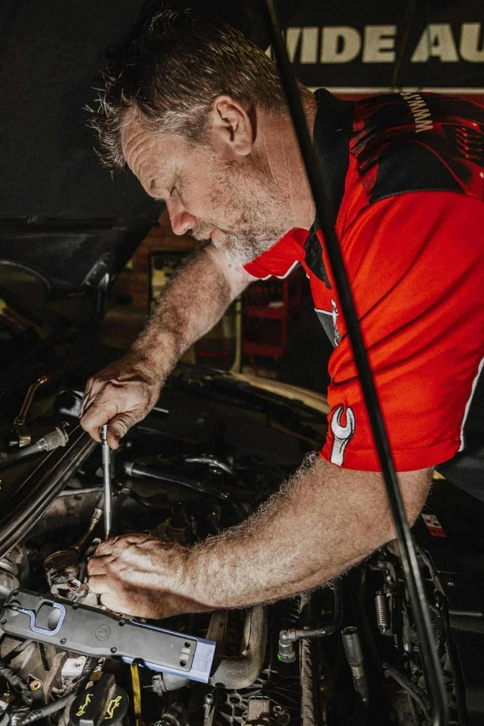 A Man in a Red Shirt is Working on a Car Engine — Nationwide Auto Service Centre in West Gosford, NSW