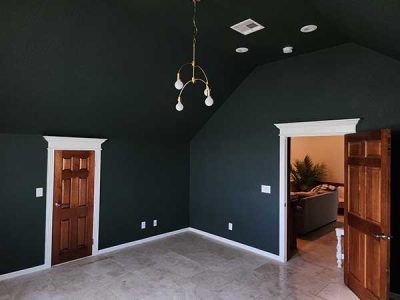 An empty room with a vaulted ceiling and a chandelier hanging from the ceiling.