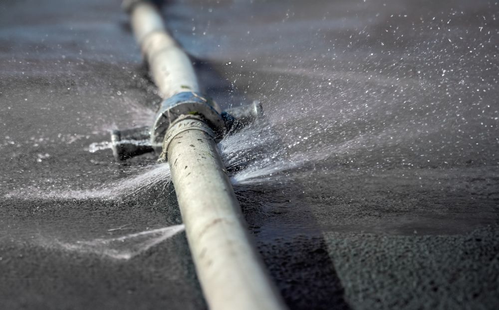 A broken pipe is spraying water on the ground.