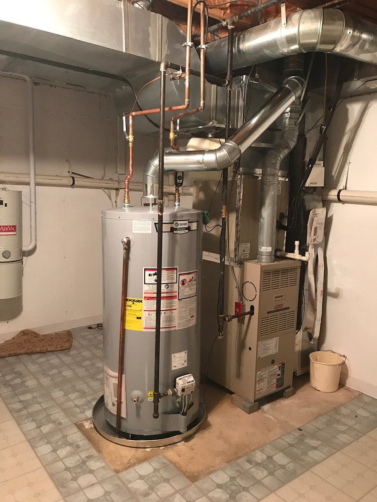 Water heater and furnace in a utility room with silver ductwork and copper pipes.