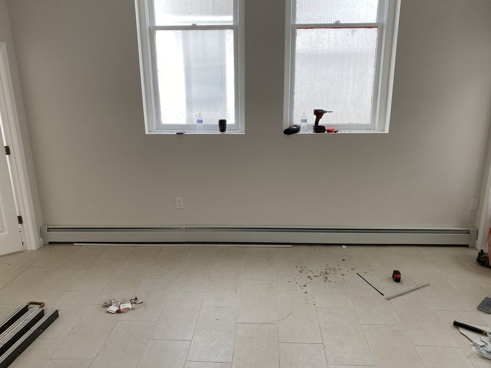Empty room with two windows, a baseboard heater, and scattered tools.